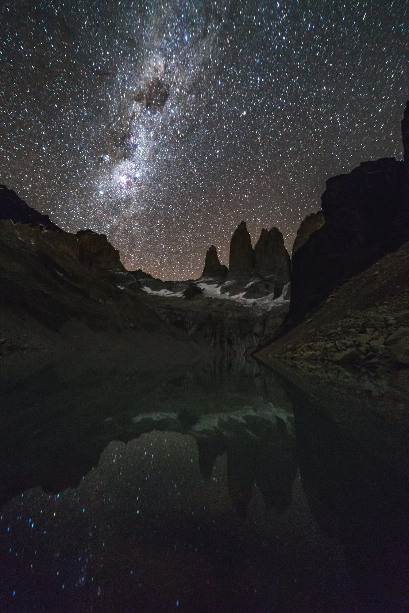 The Milky Way above tall granite towers reflected in a still mountain lake