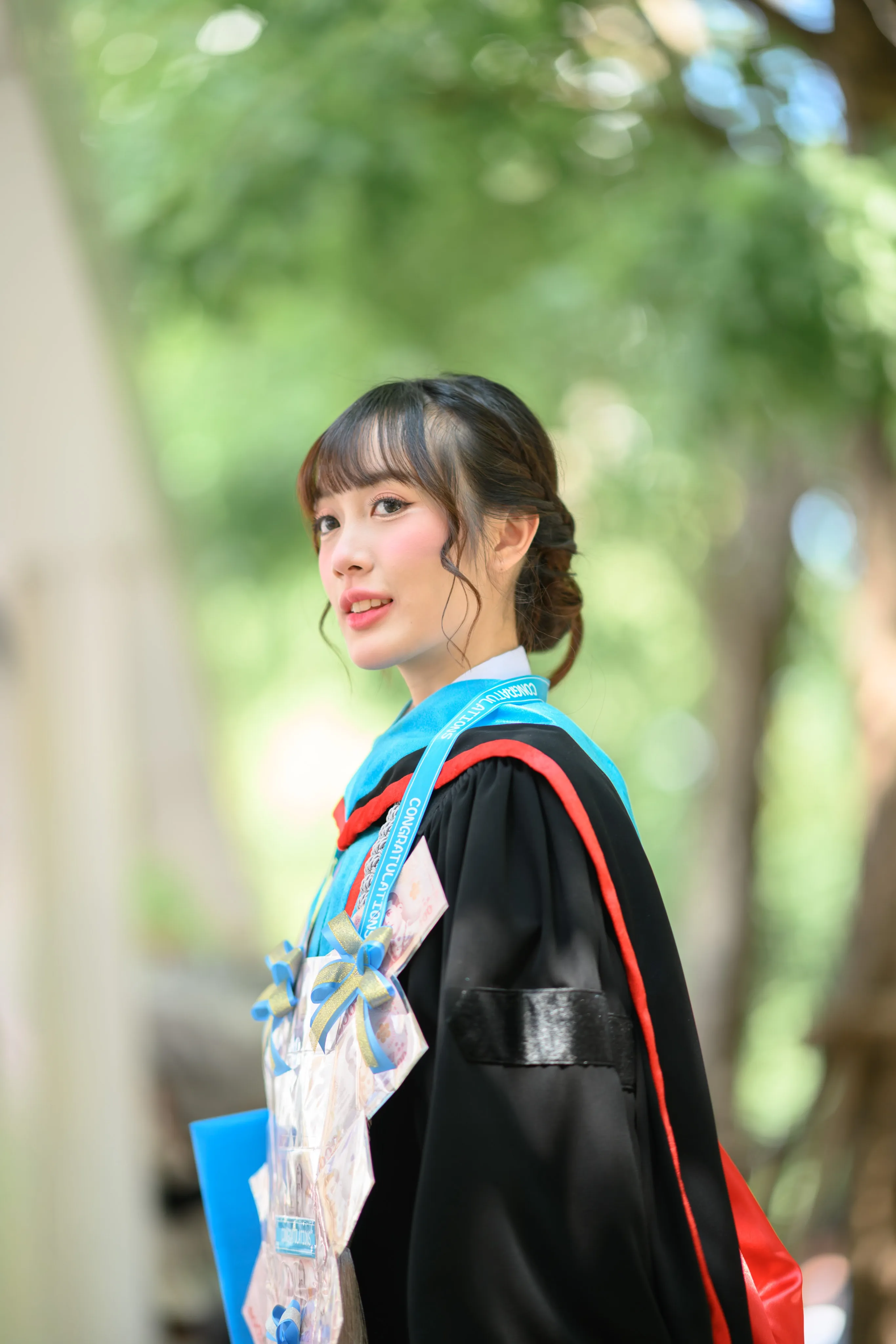 A graduate in cap and gown looking off to the side outdoors