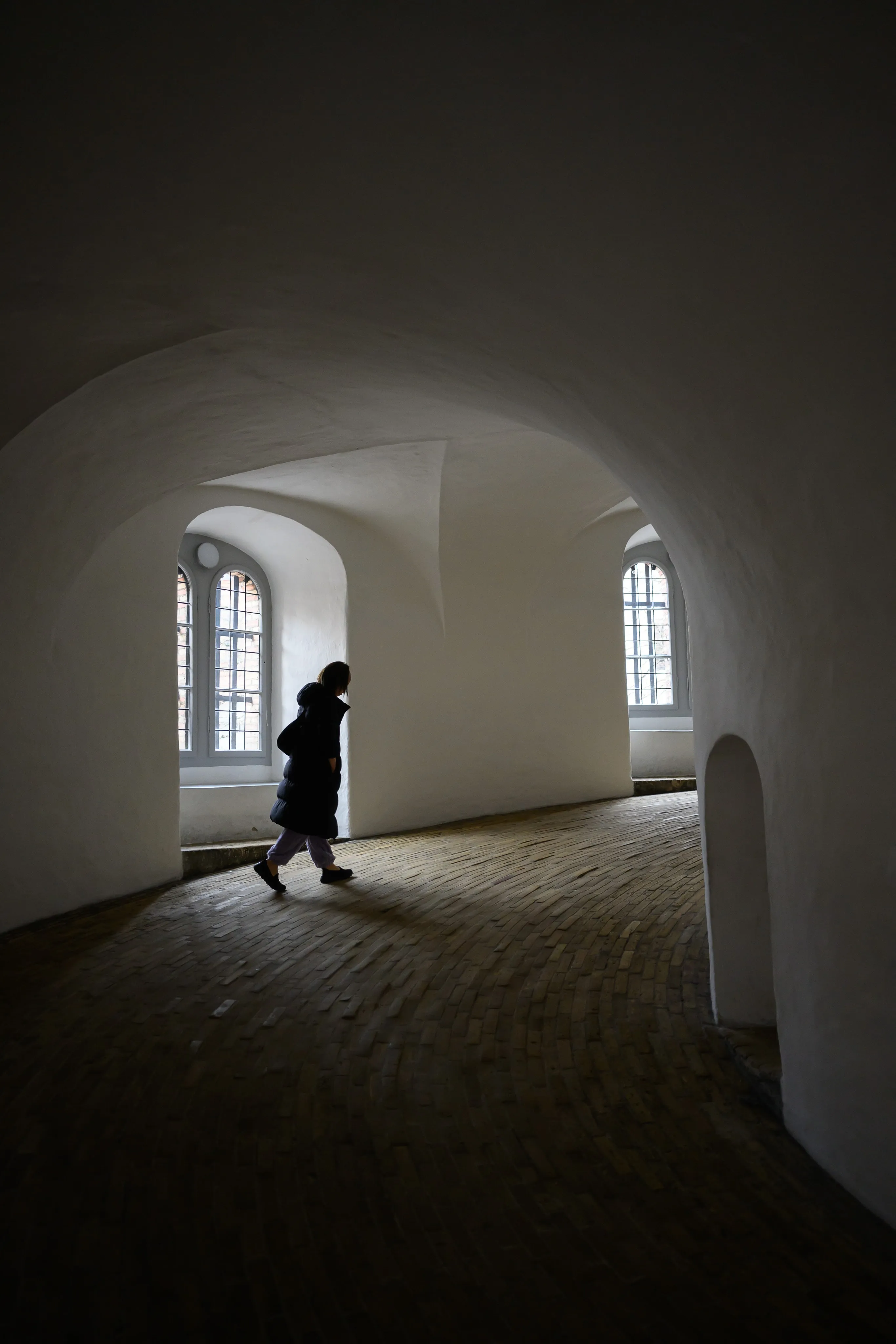 A silhouette walking through a bright white archway