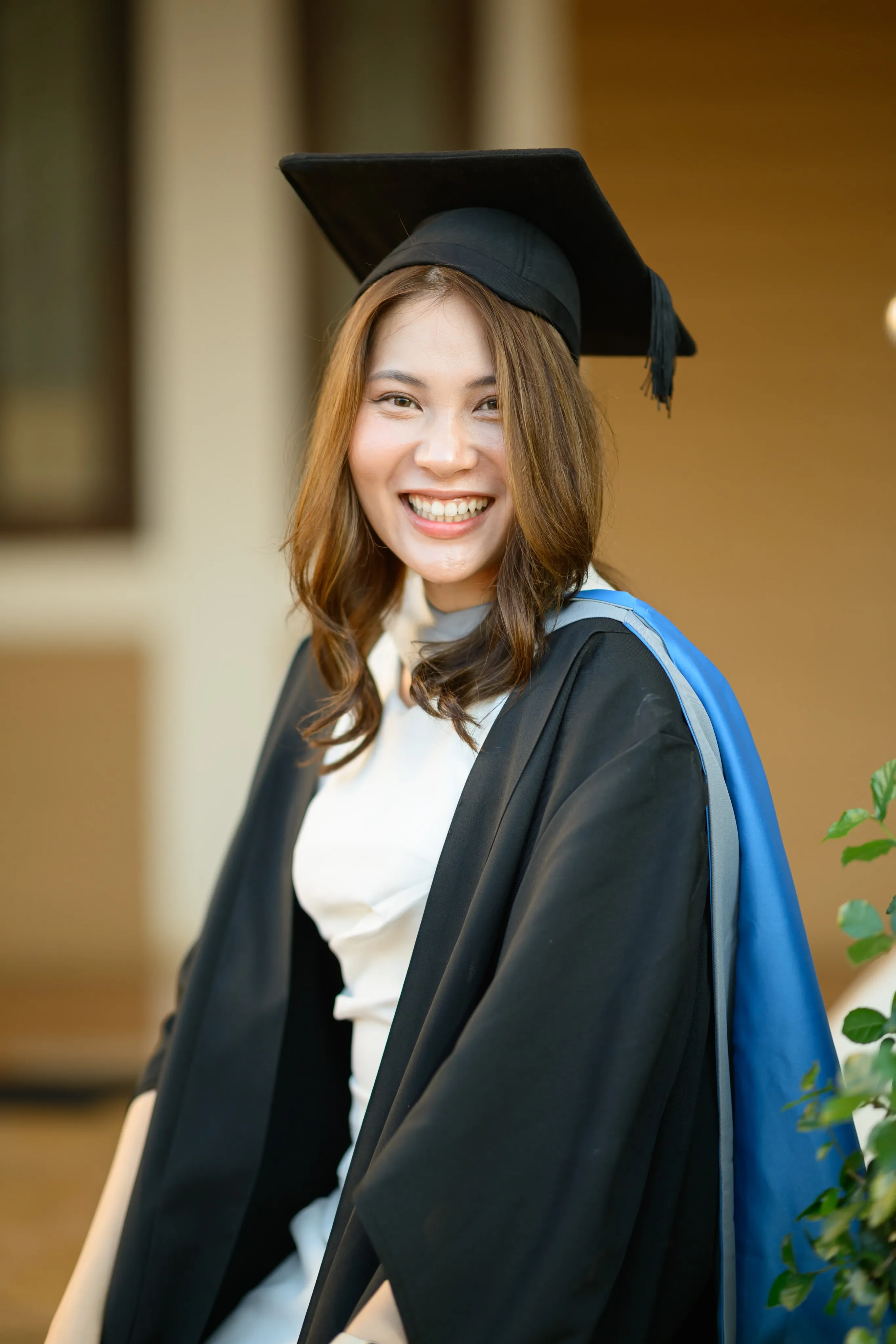 A graduate smiling warmly in front of a building