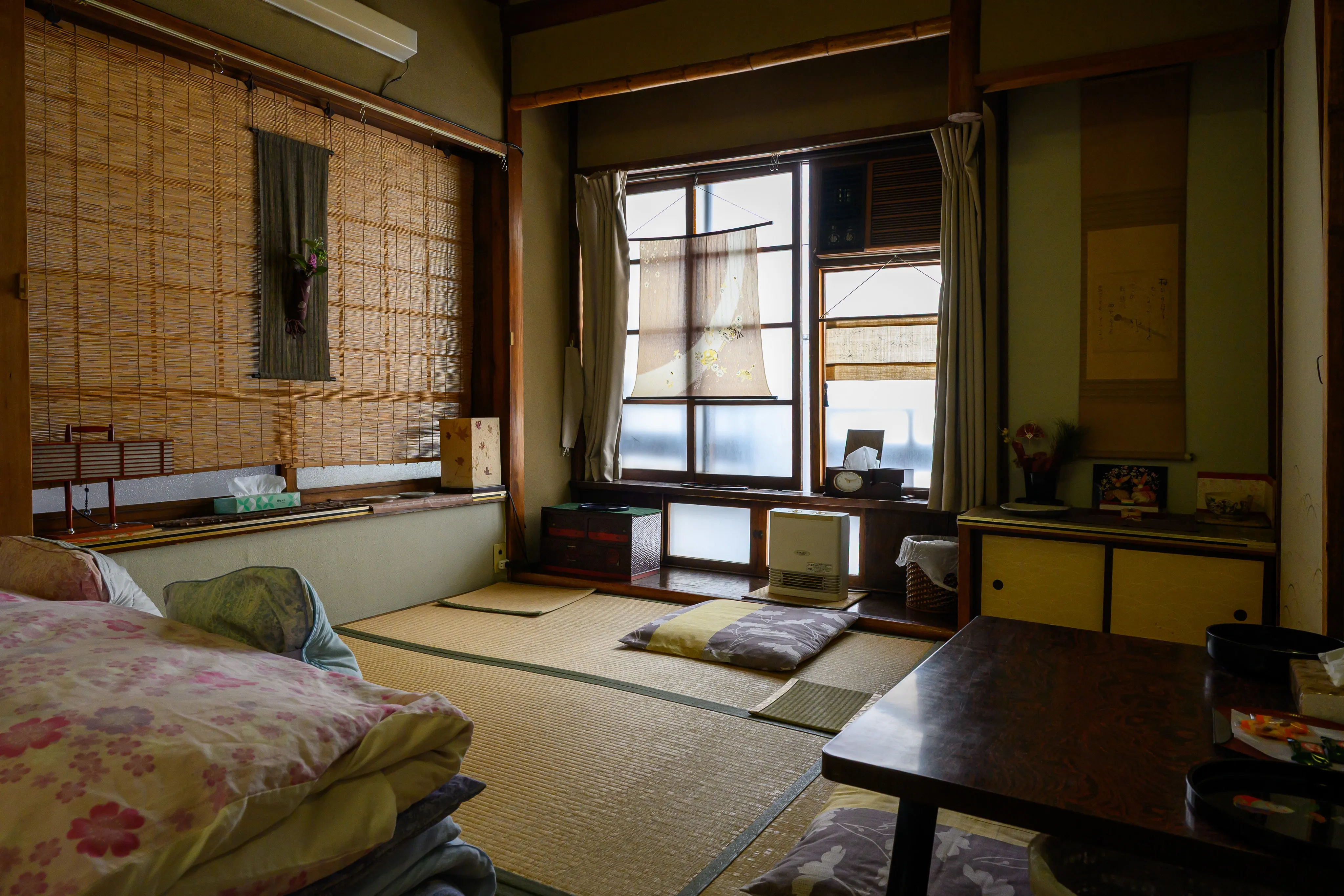 Traditional Japanese tatami room with floor cushions, low tables, and bamboo blinds