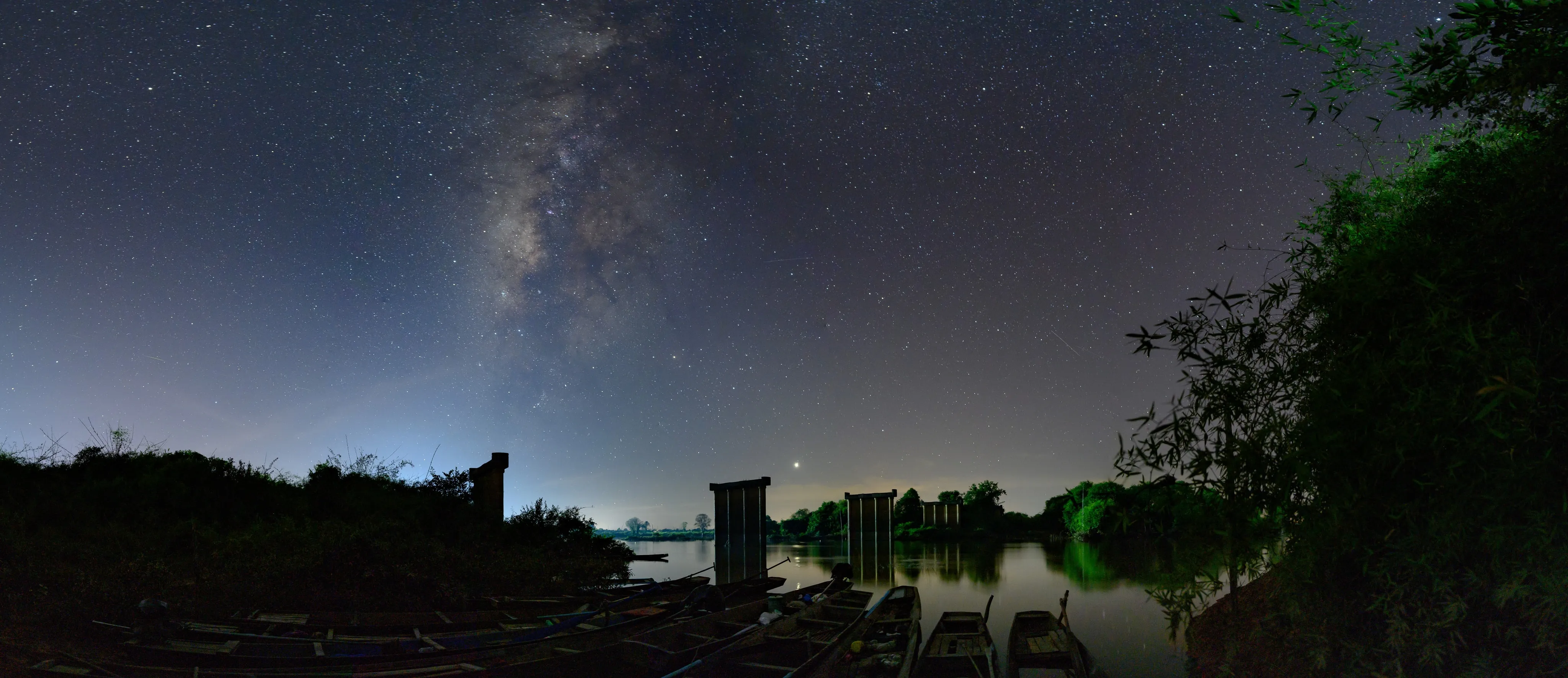 The Milky Way above a lakeside building and trees