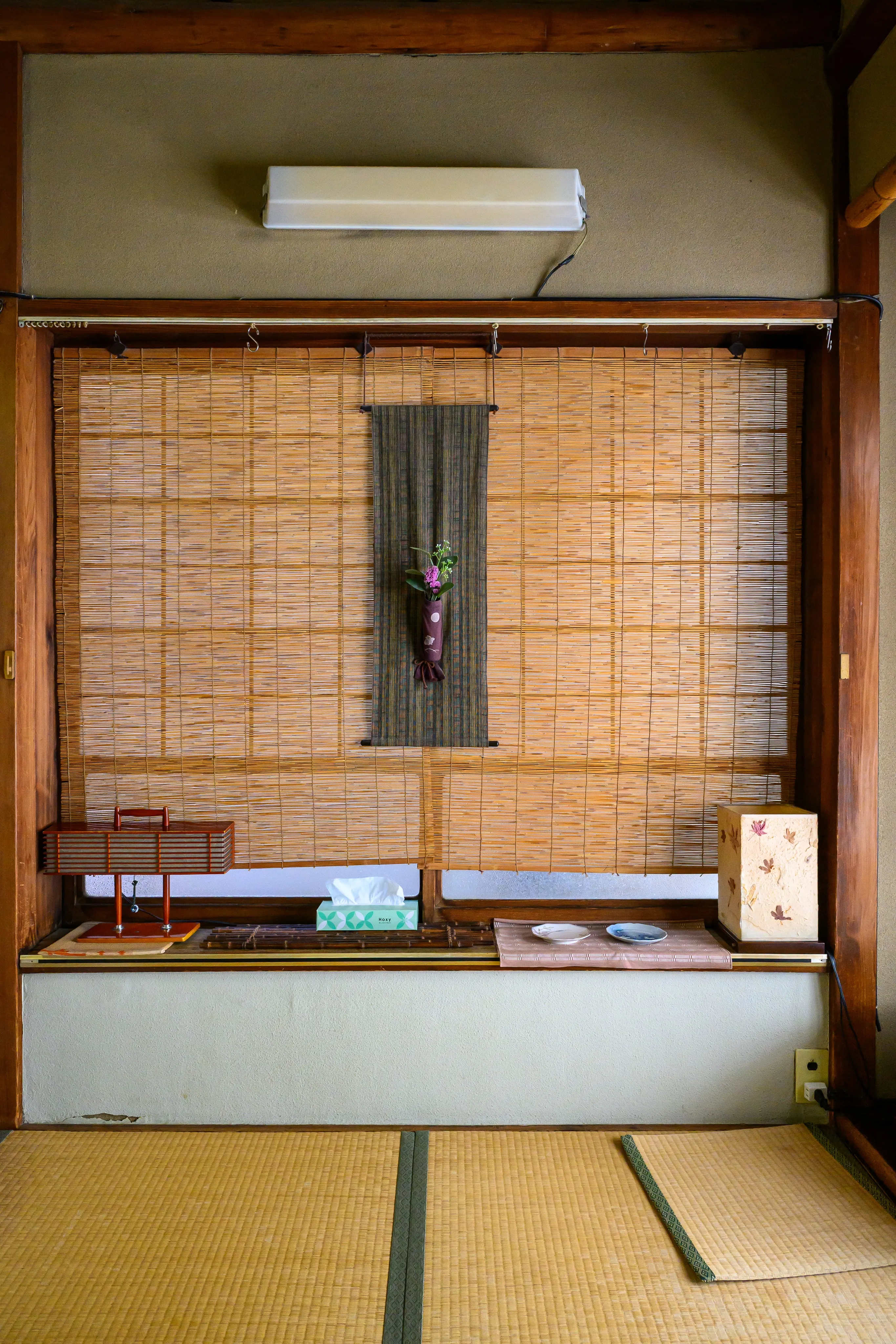 Bamboo-screened alcove with tatami flooring and a hanging flower arrangement