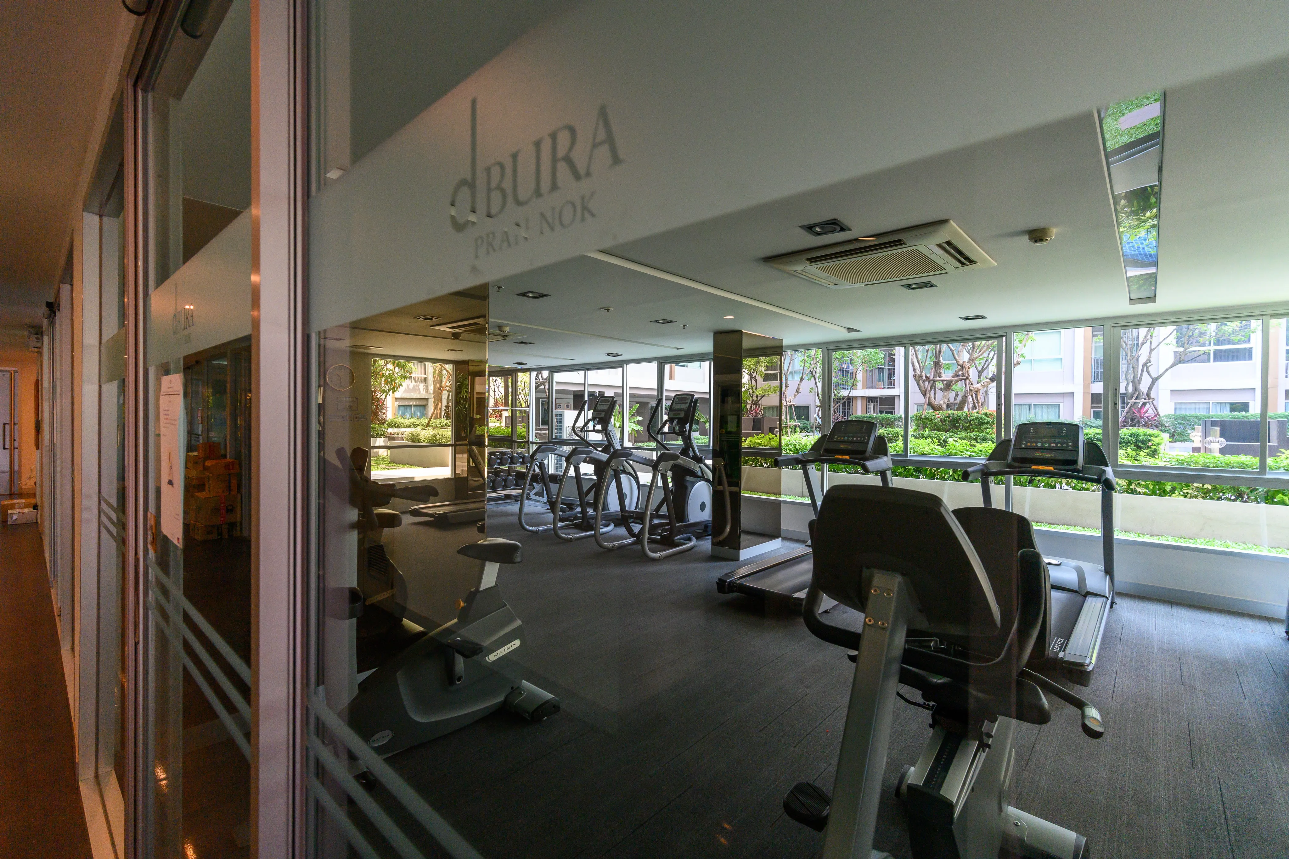 Condominium fitness room with exercise machines facing large windows