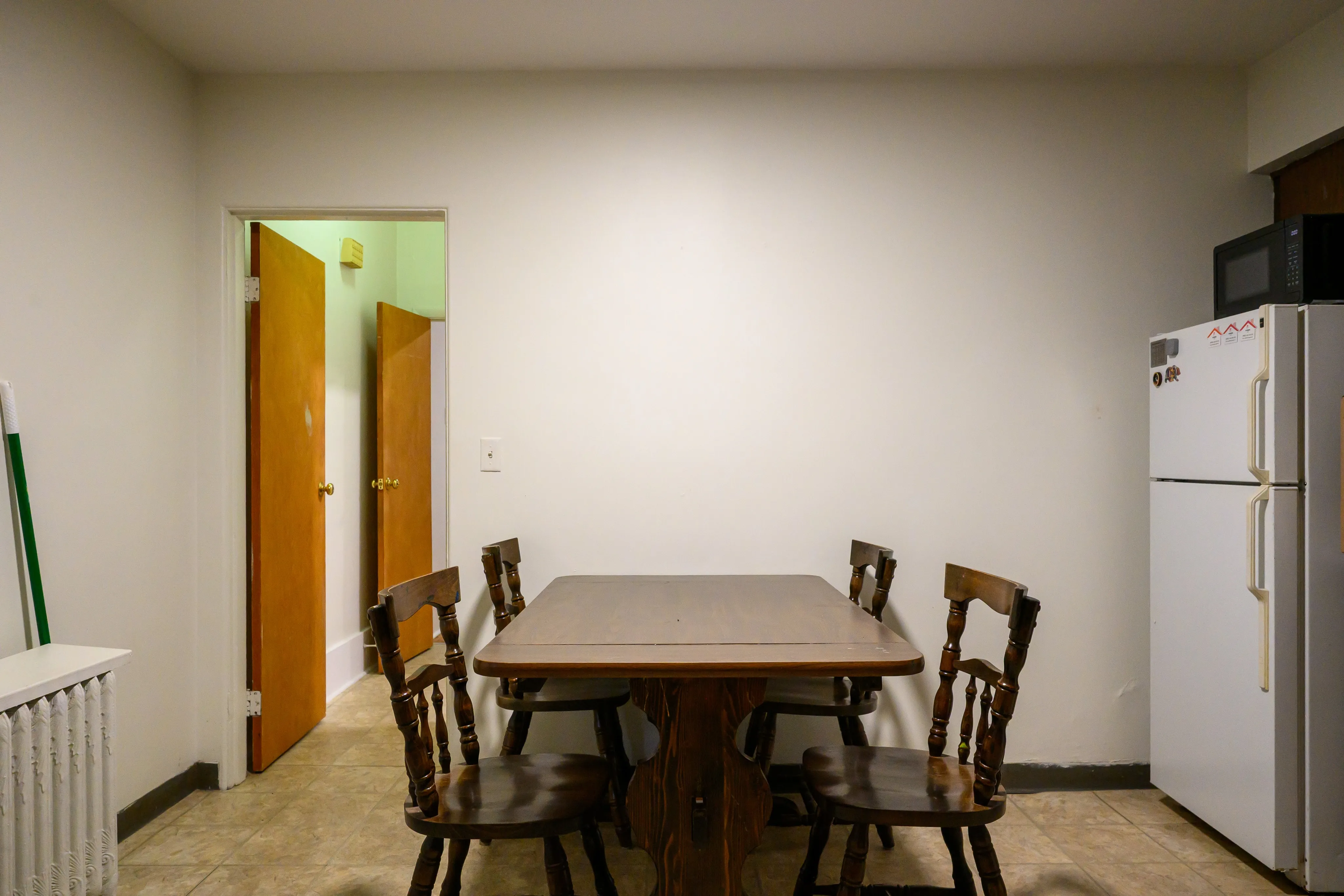 Plain apartment dining area with a wooden table beside an open doorway