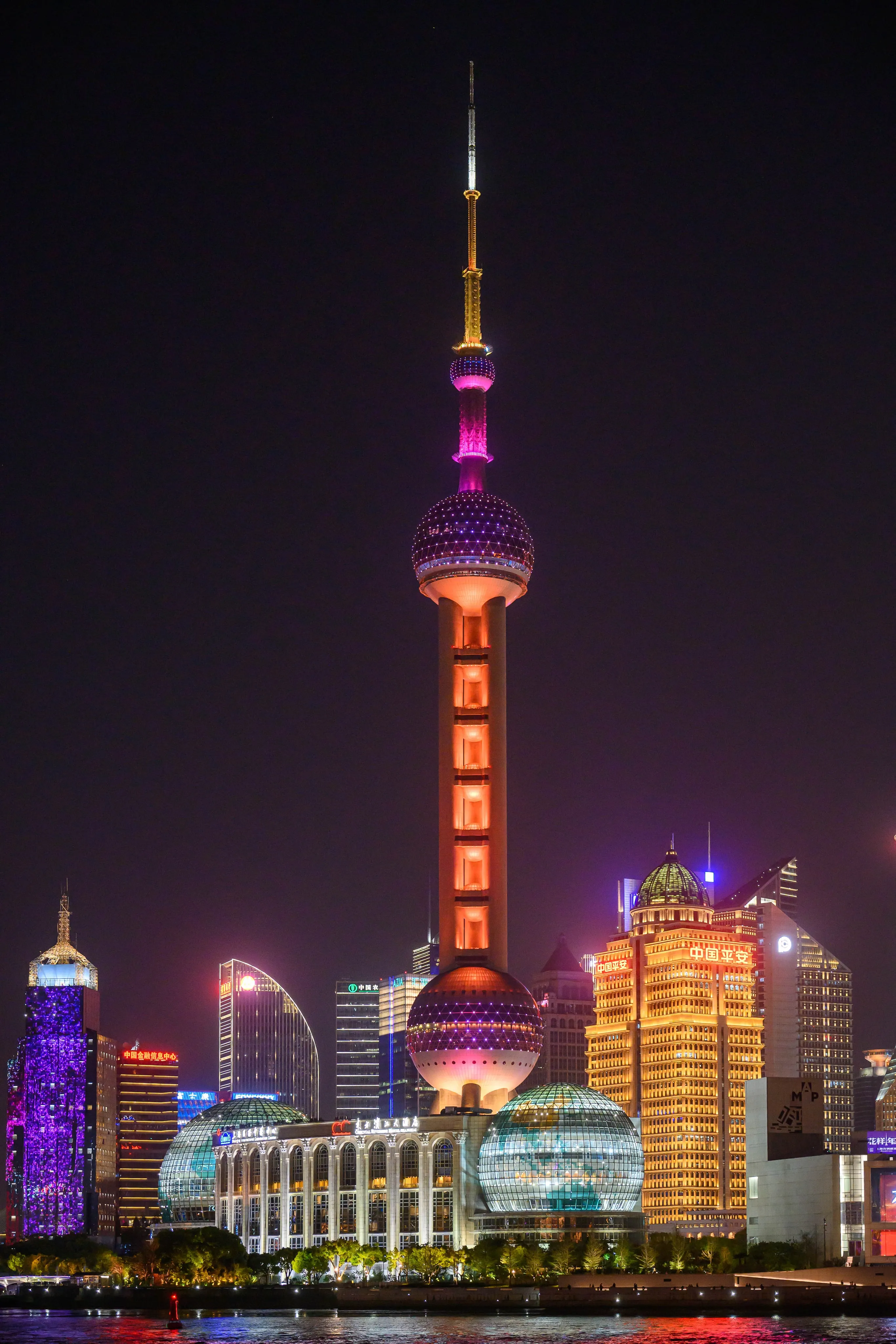 A city skyline lit up at night with a tall illuminated tower