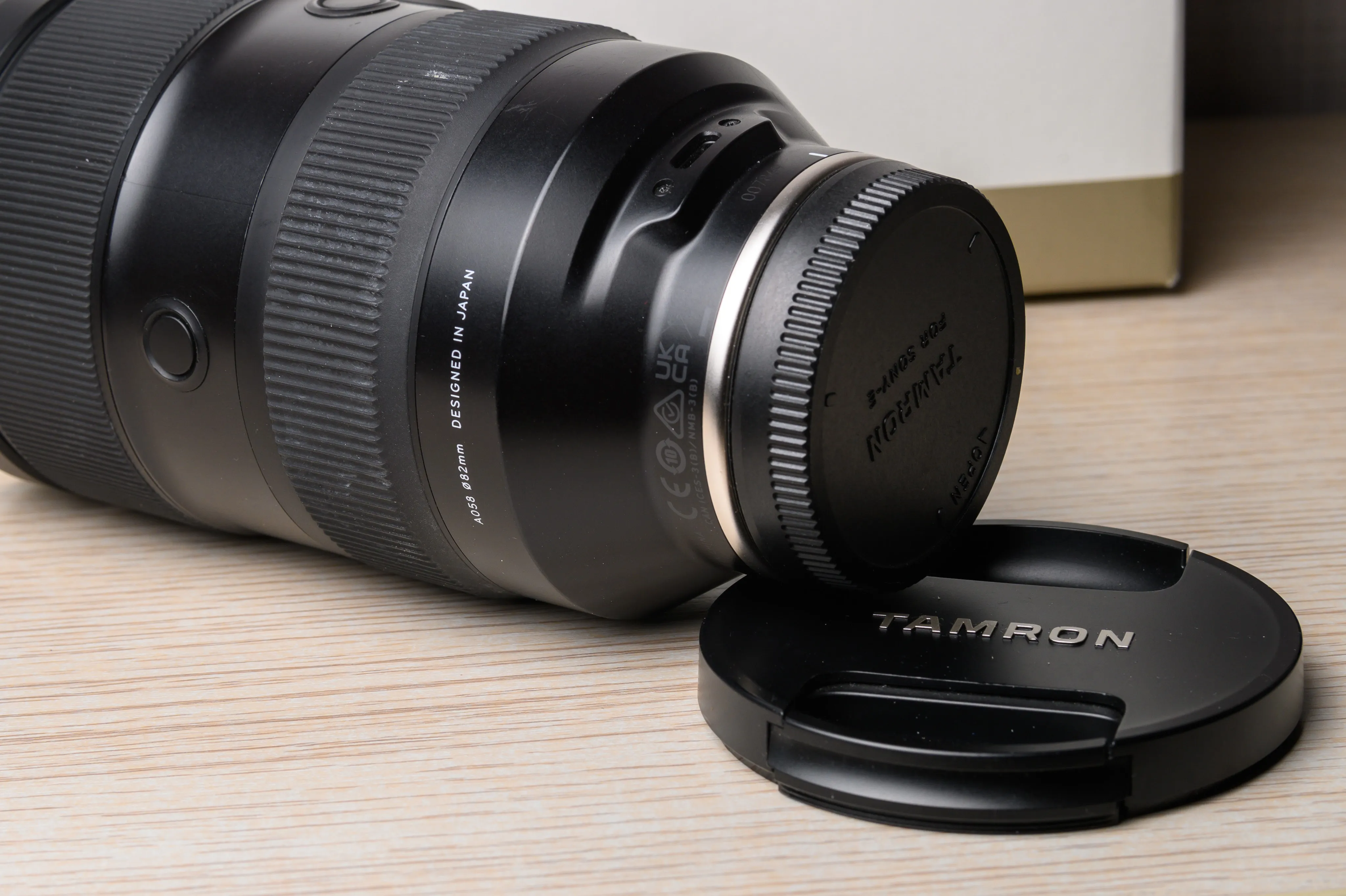 A camera lens resting on a tabletop beside its cap