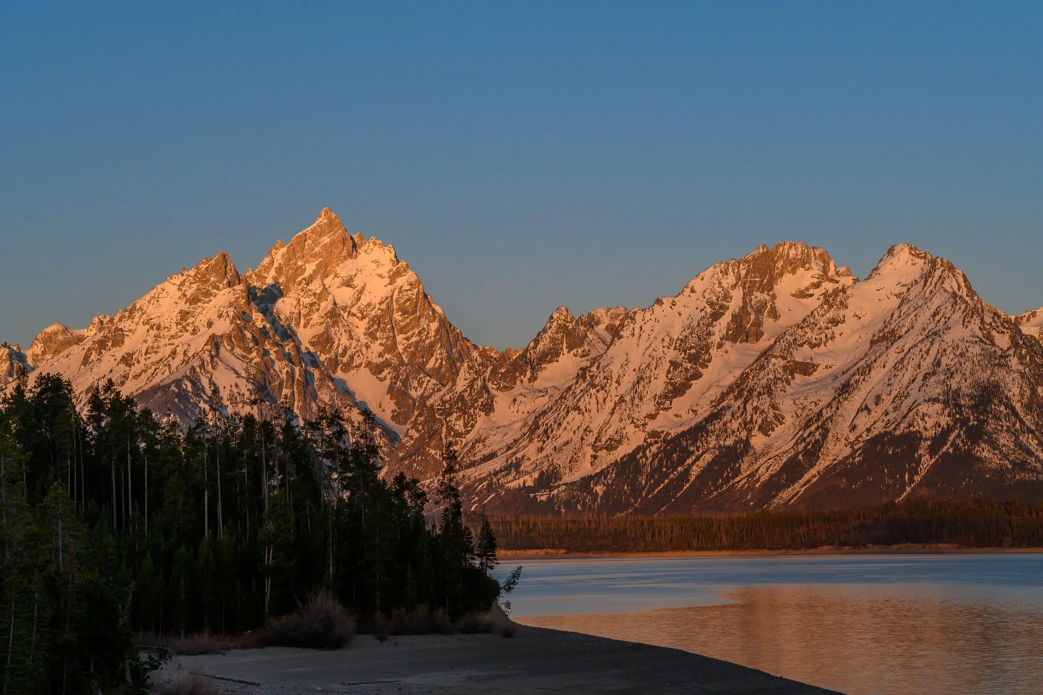 Jagged mountain range reflected in a calm lake at sunset