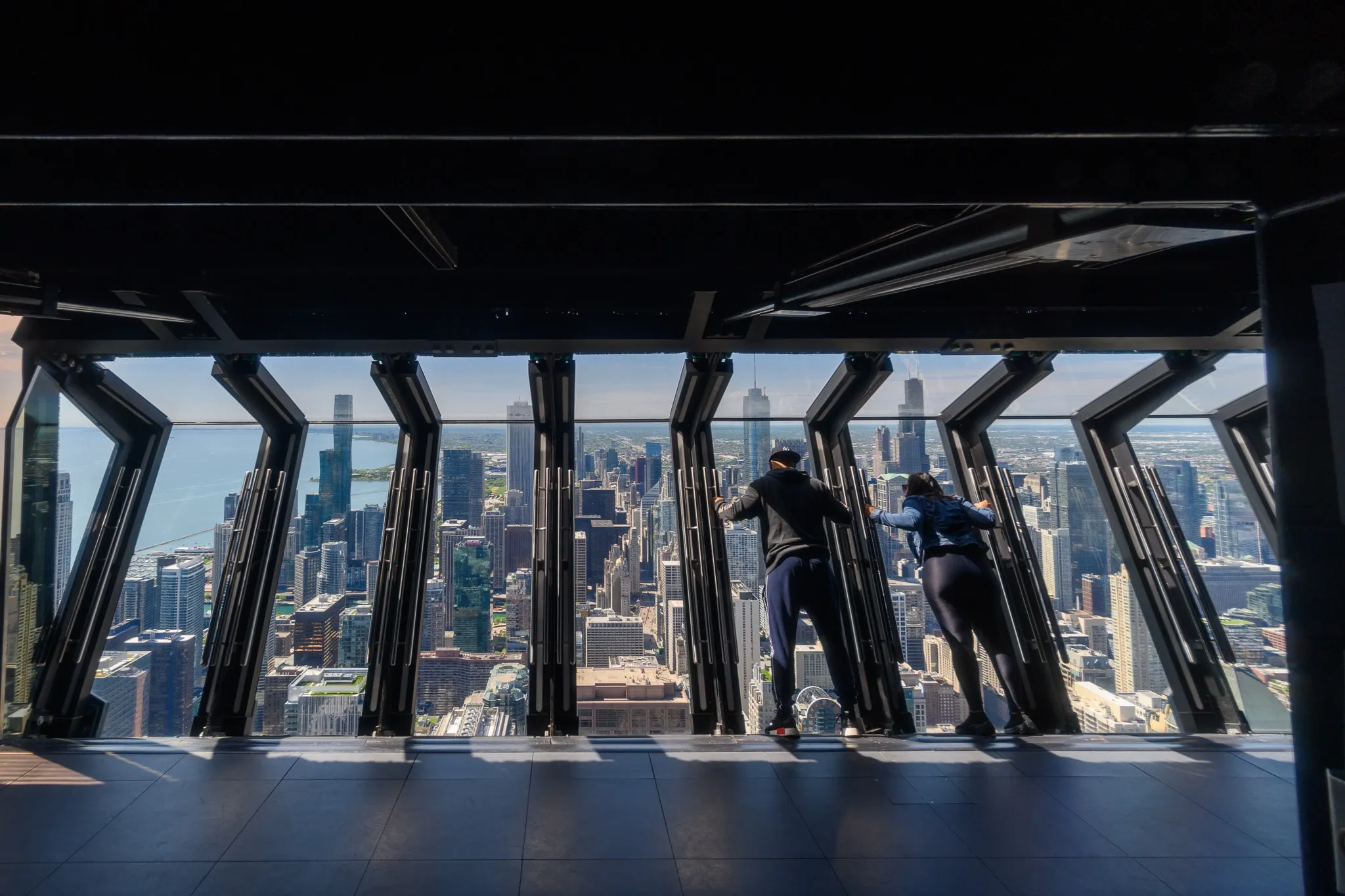 Visitors looking across a city skyline from inside a glass observation deck