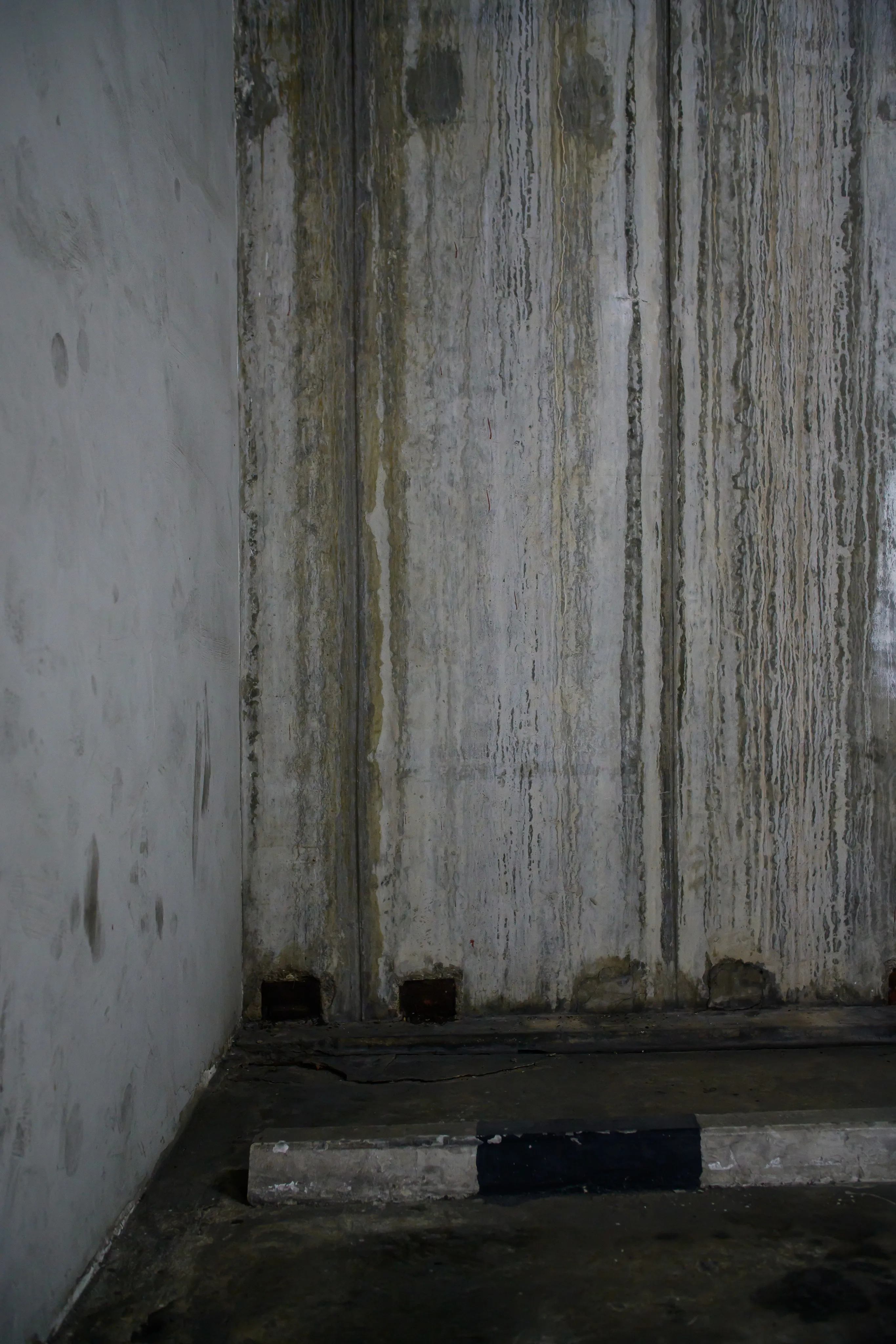 An empty concrete stairwell corner, dimly lit.
