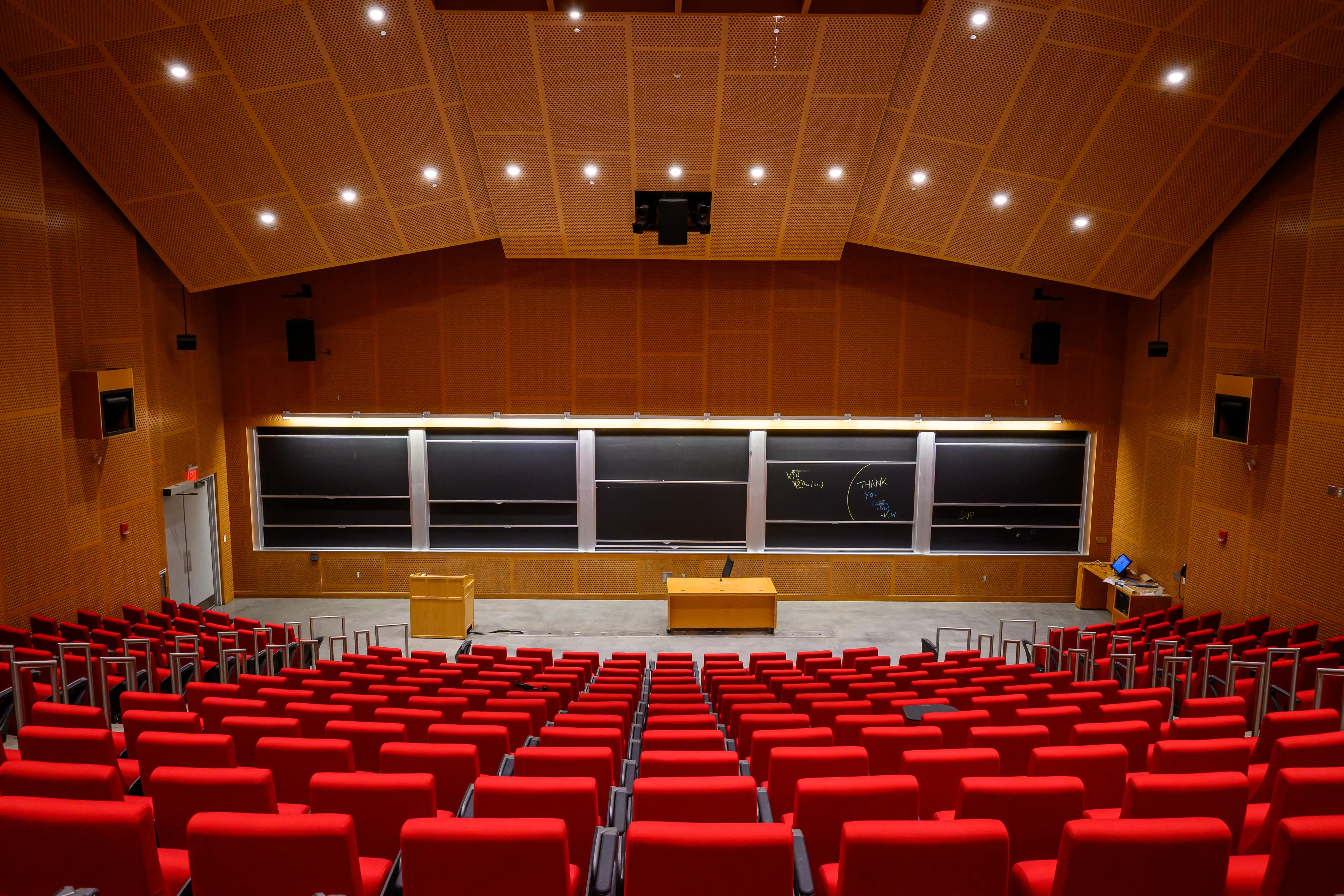 Rows of red seats inside a wood-paneled auditorium