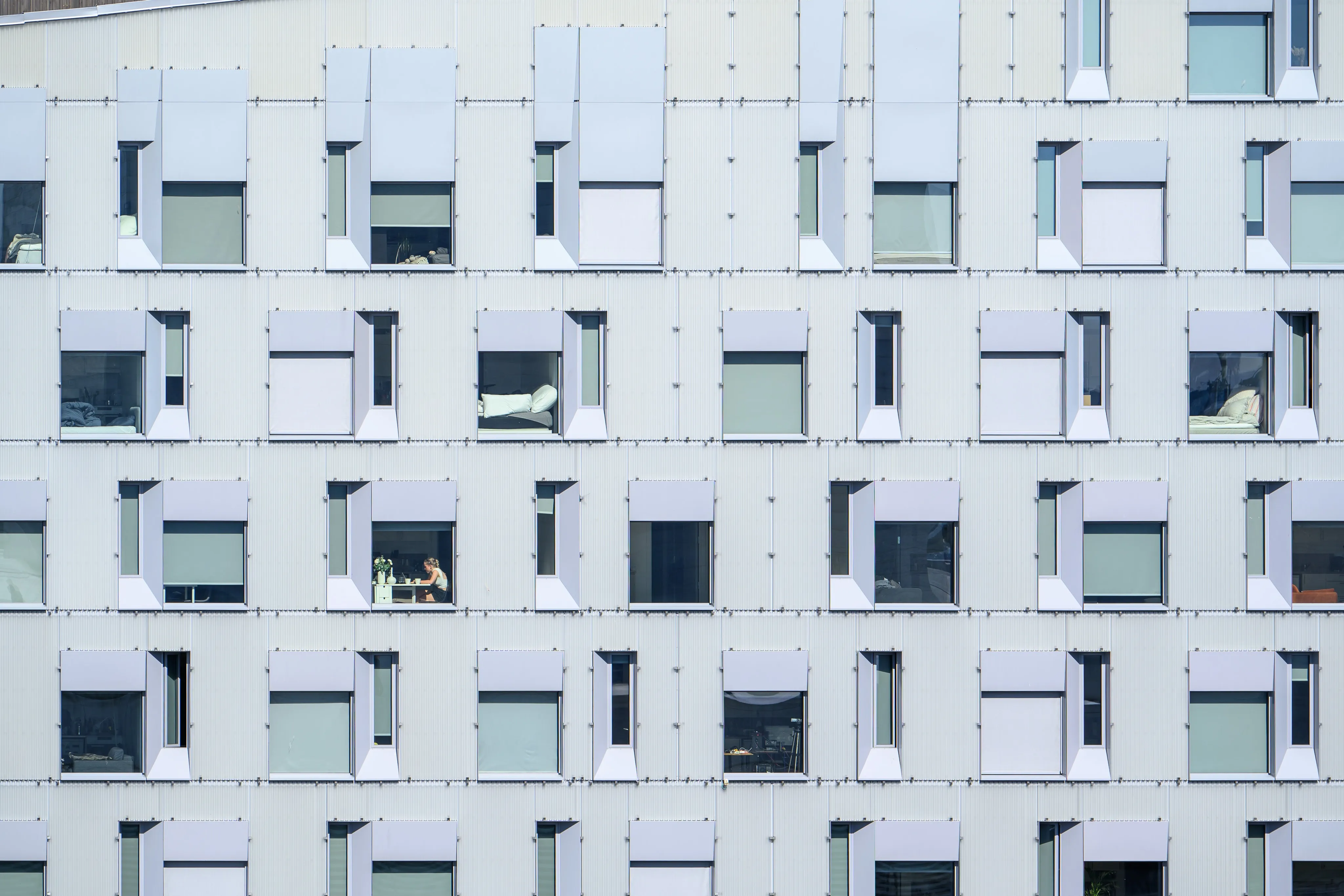 A modern glass office building facade with a repeating window pattern