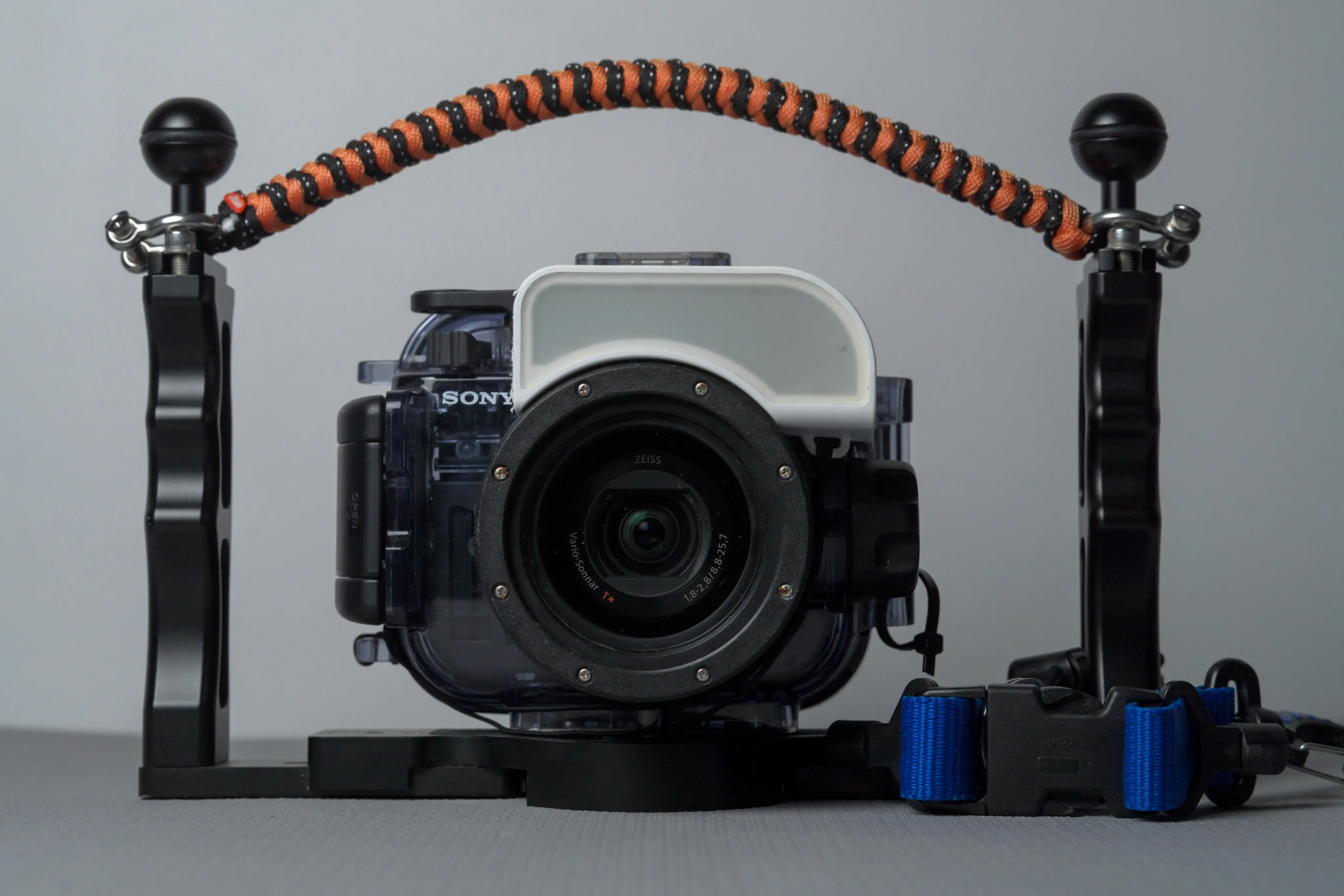 A camera inside a housing with an orange handle