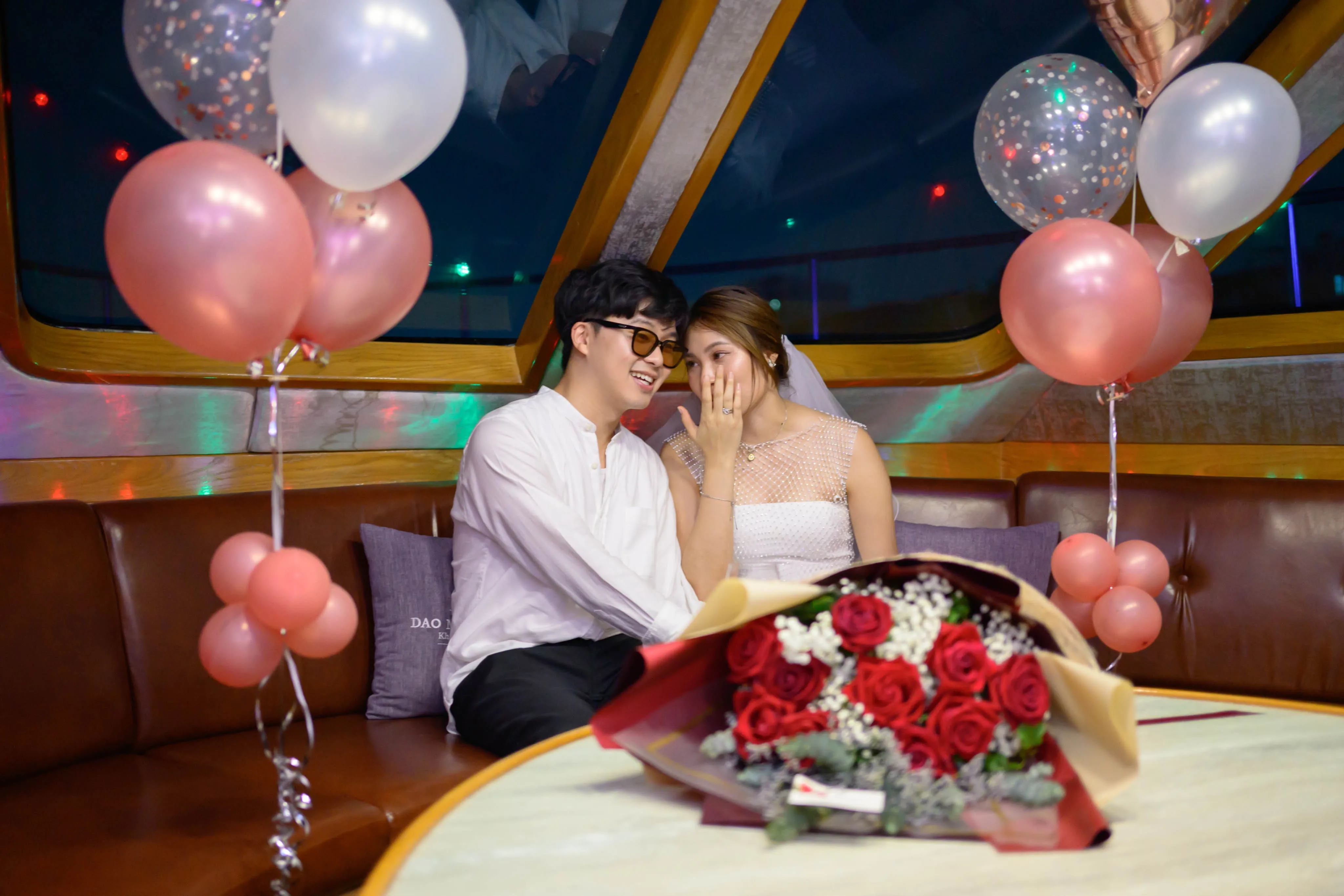 A couple embracing on a boat surrounded by balloons and roses