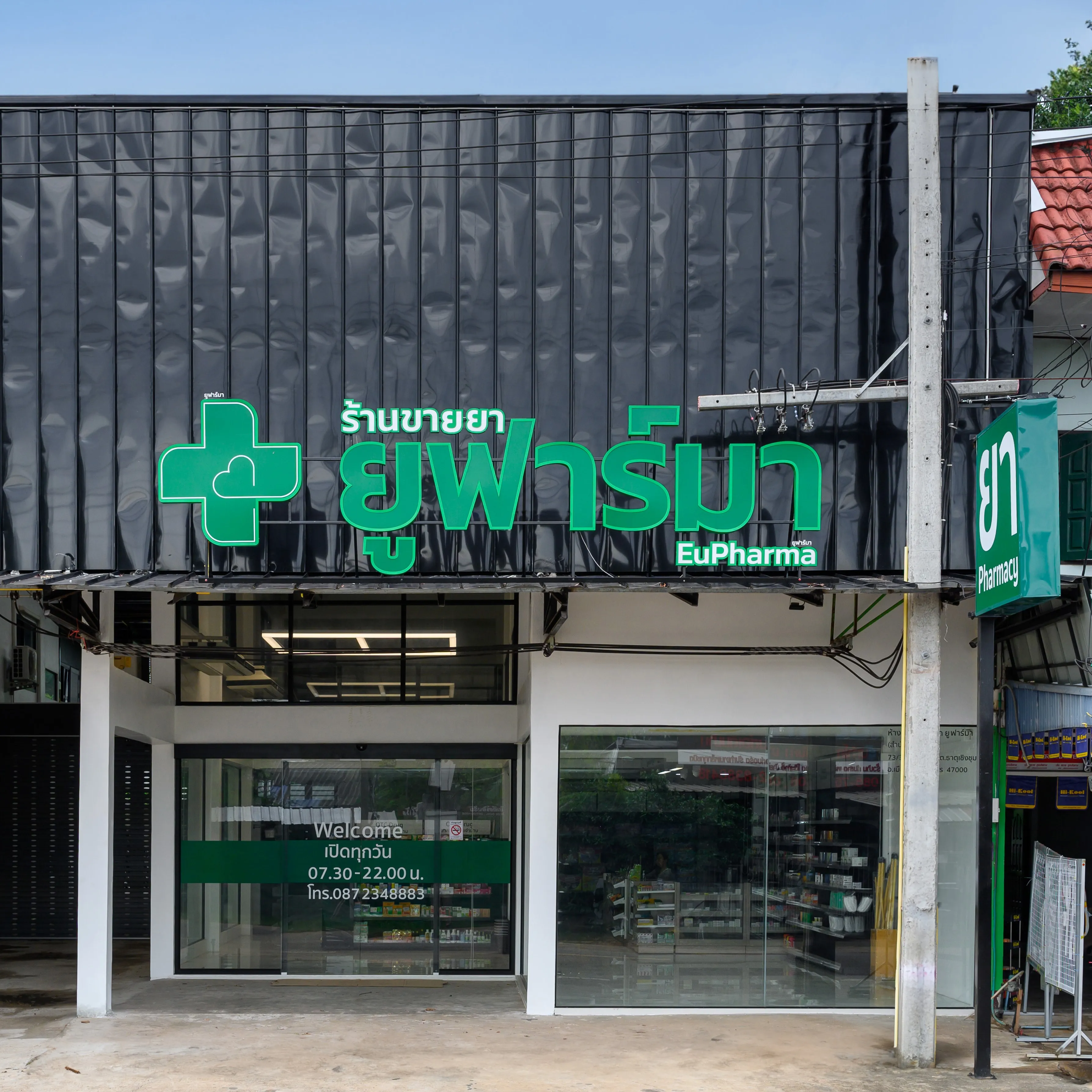 A pharmacy storefront with a green cross sign