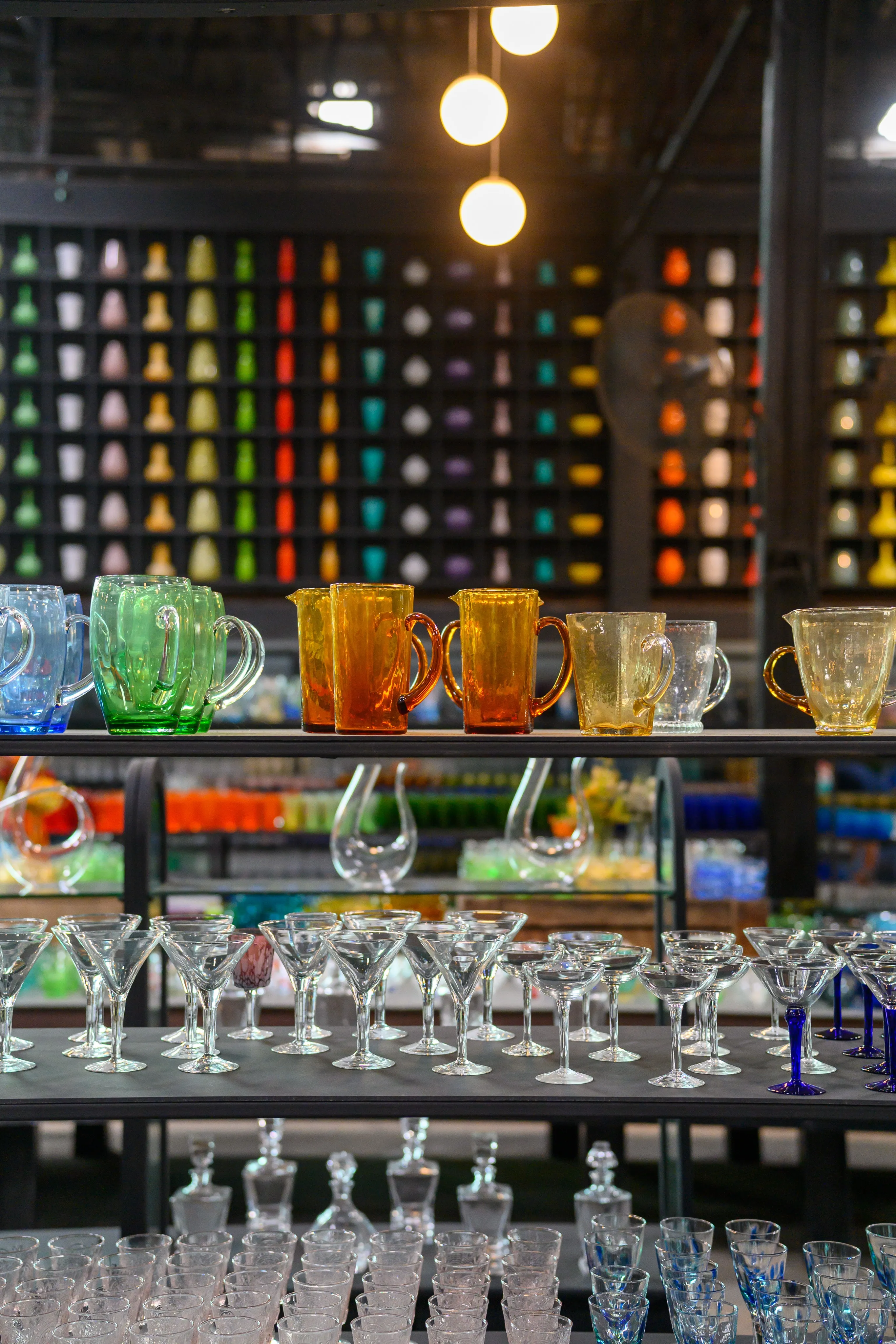 Rows of colorful glassware displayed on illuminated shelves
