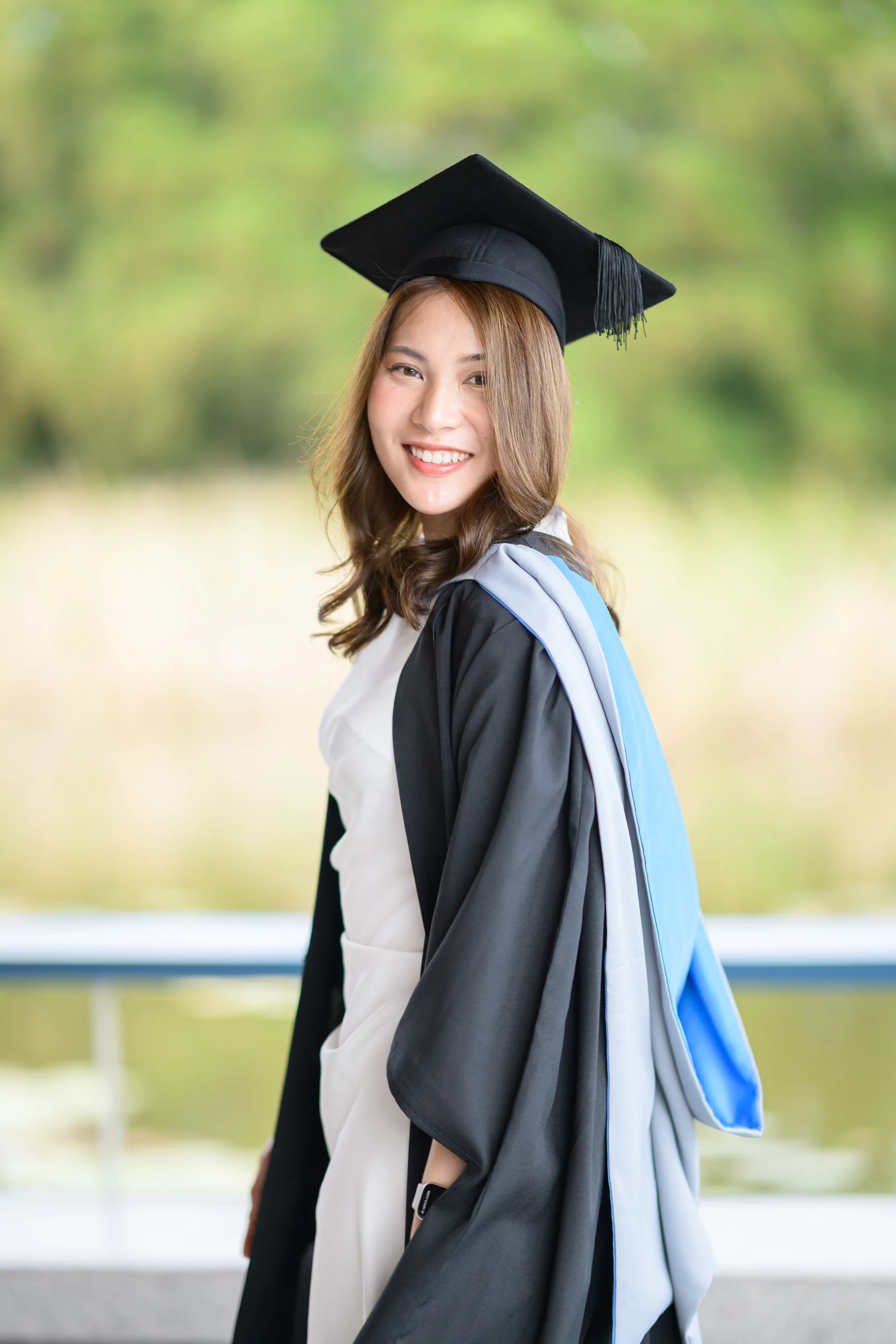 A graduate turning toward the camera against a green background