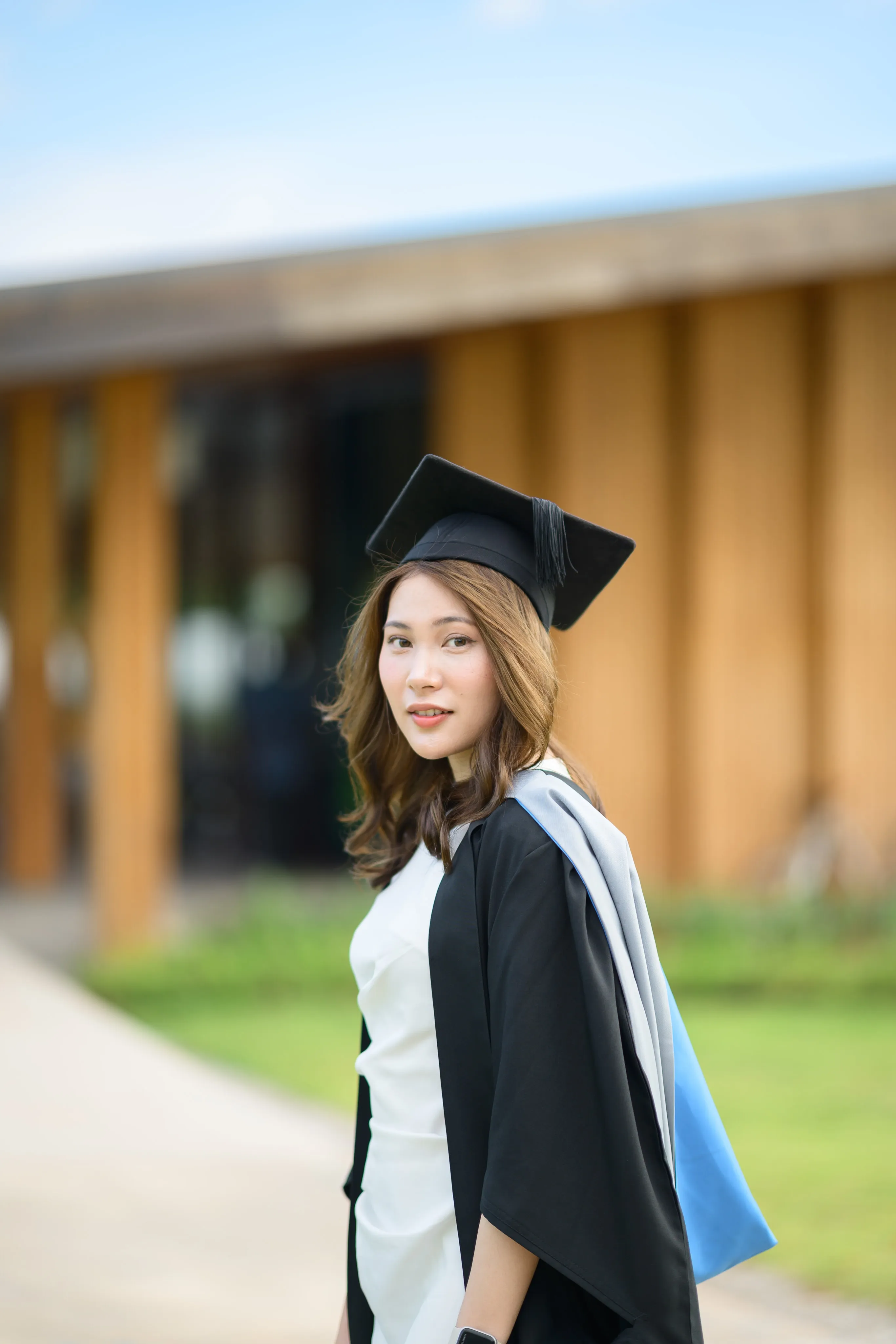 A graduate in cap and gown beside a modern building