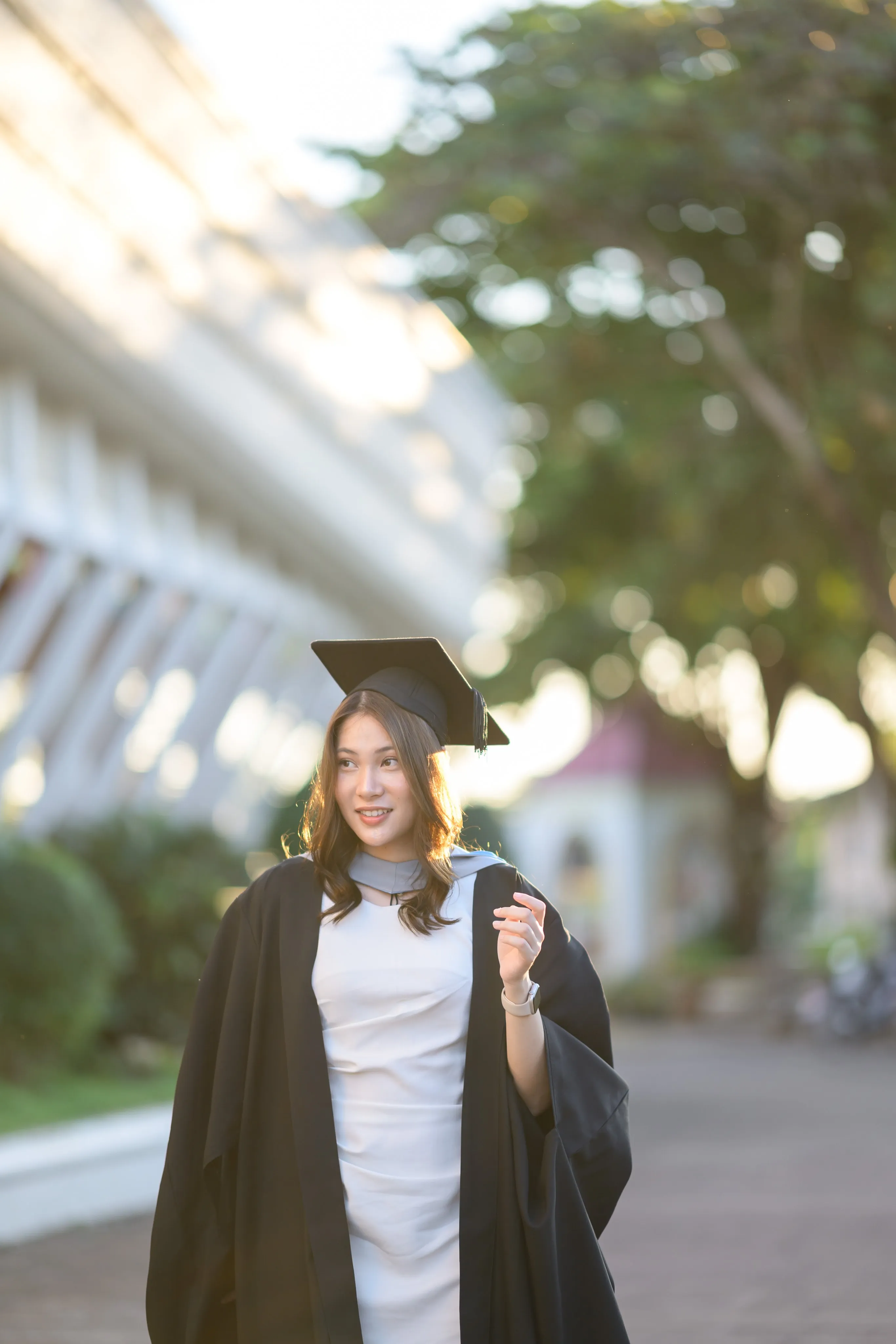 A graduate standing beside a white colonnade in warm evening light