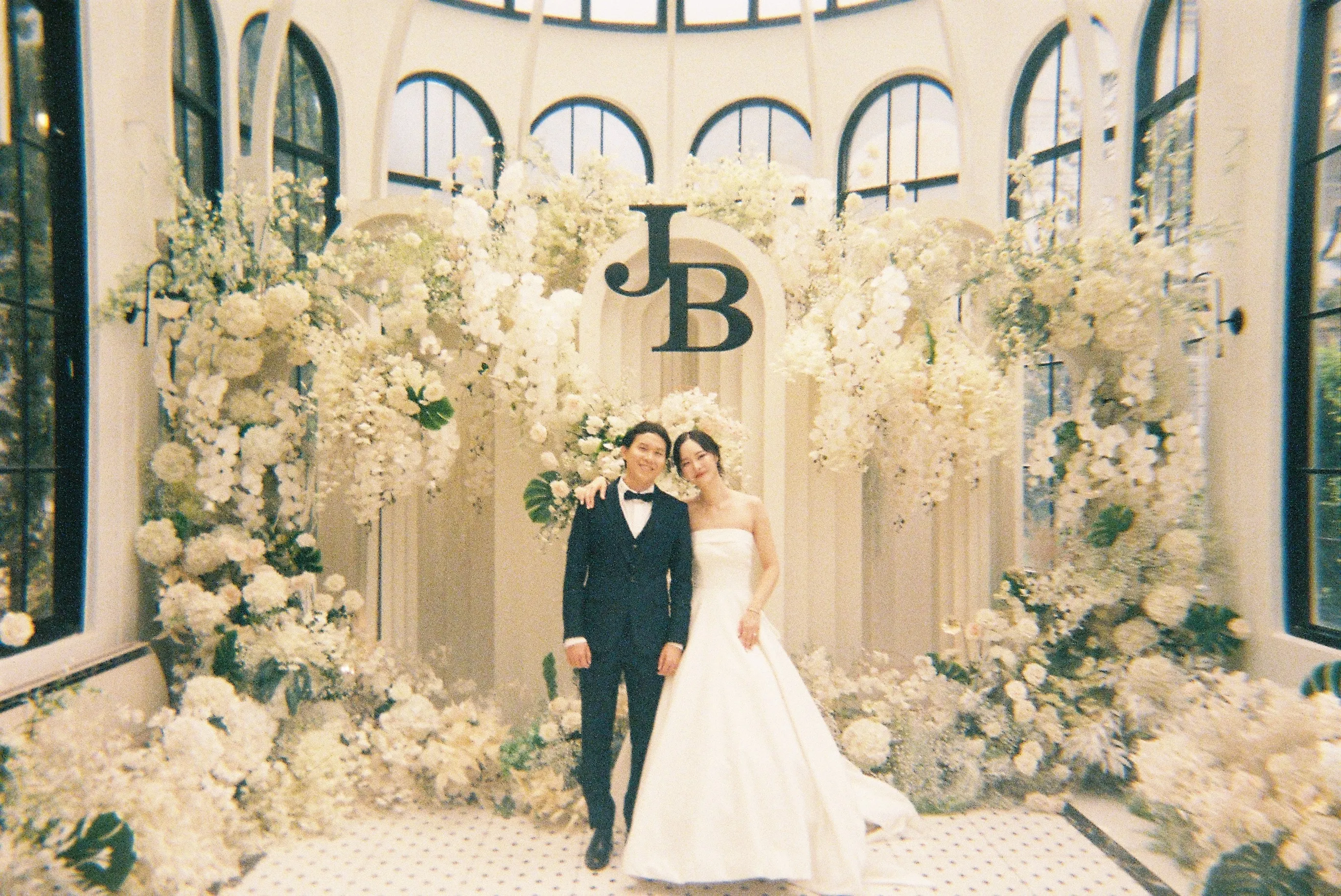 A wedding couple beneath a white floral arch