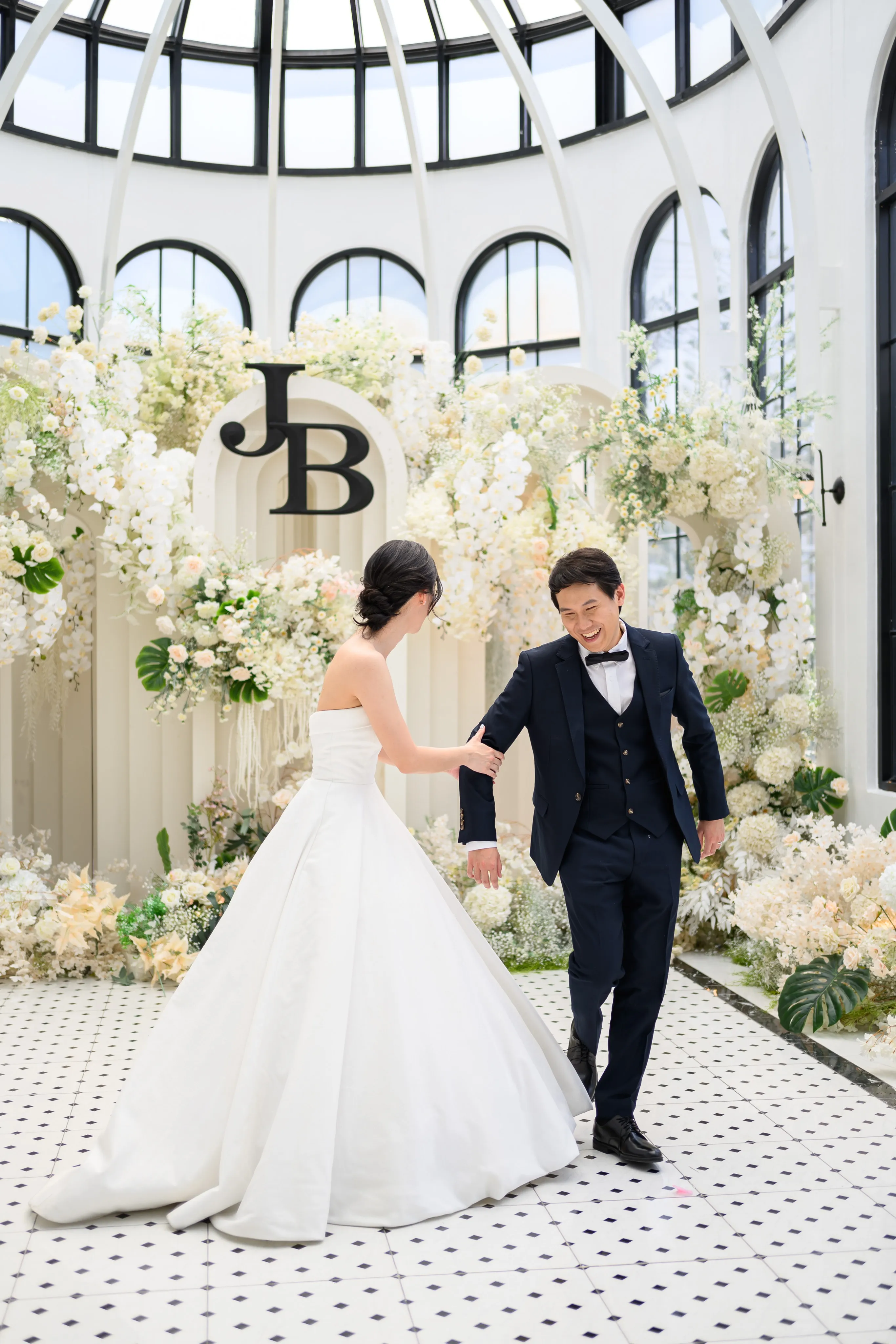 A bride and groom looking toward each other beneath a floral arch