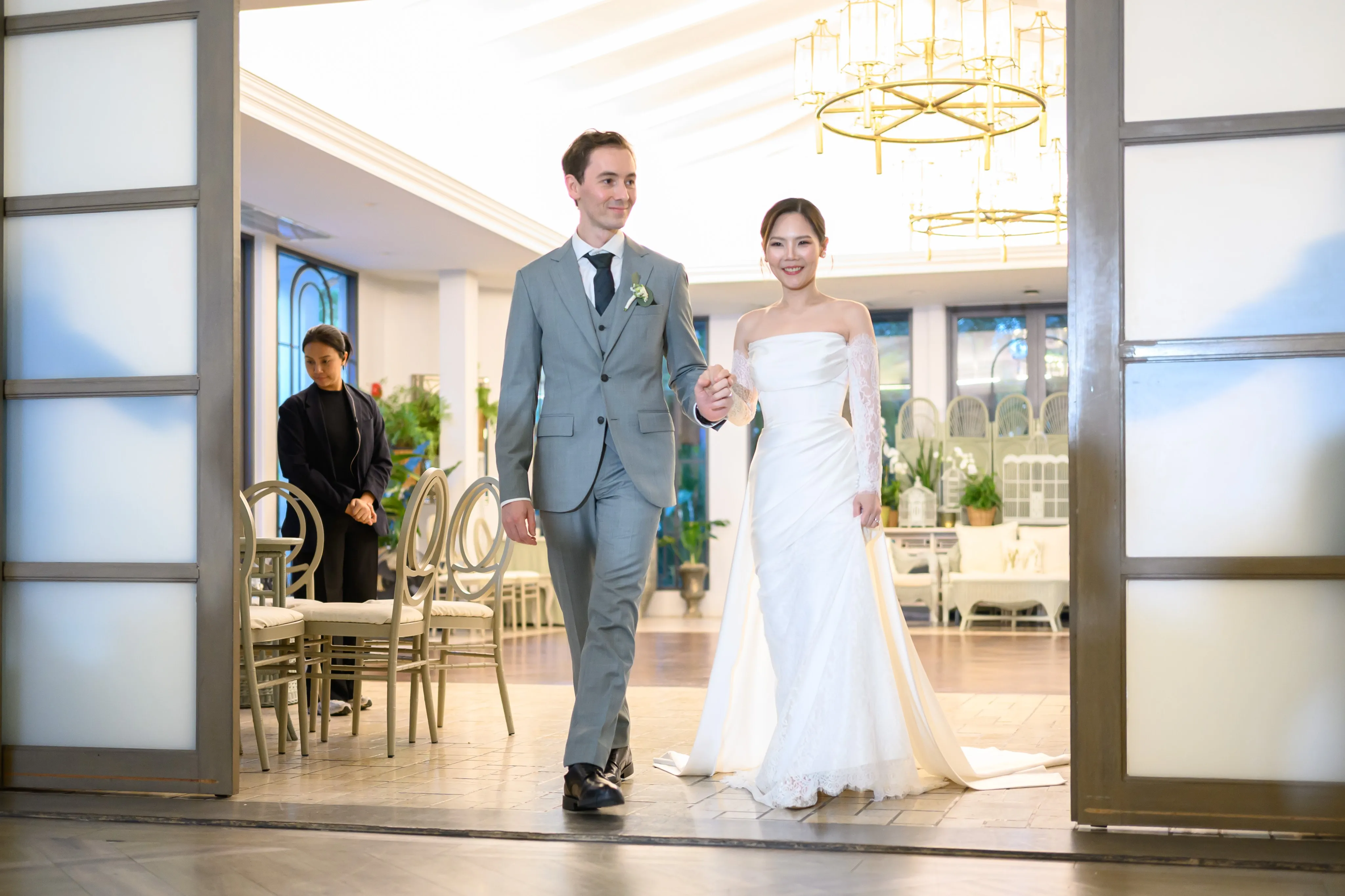 A bride and groom entering a bright room together