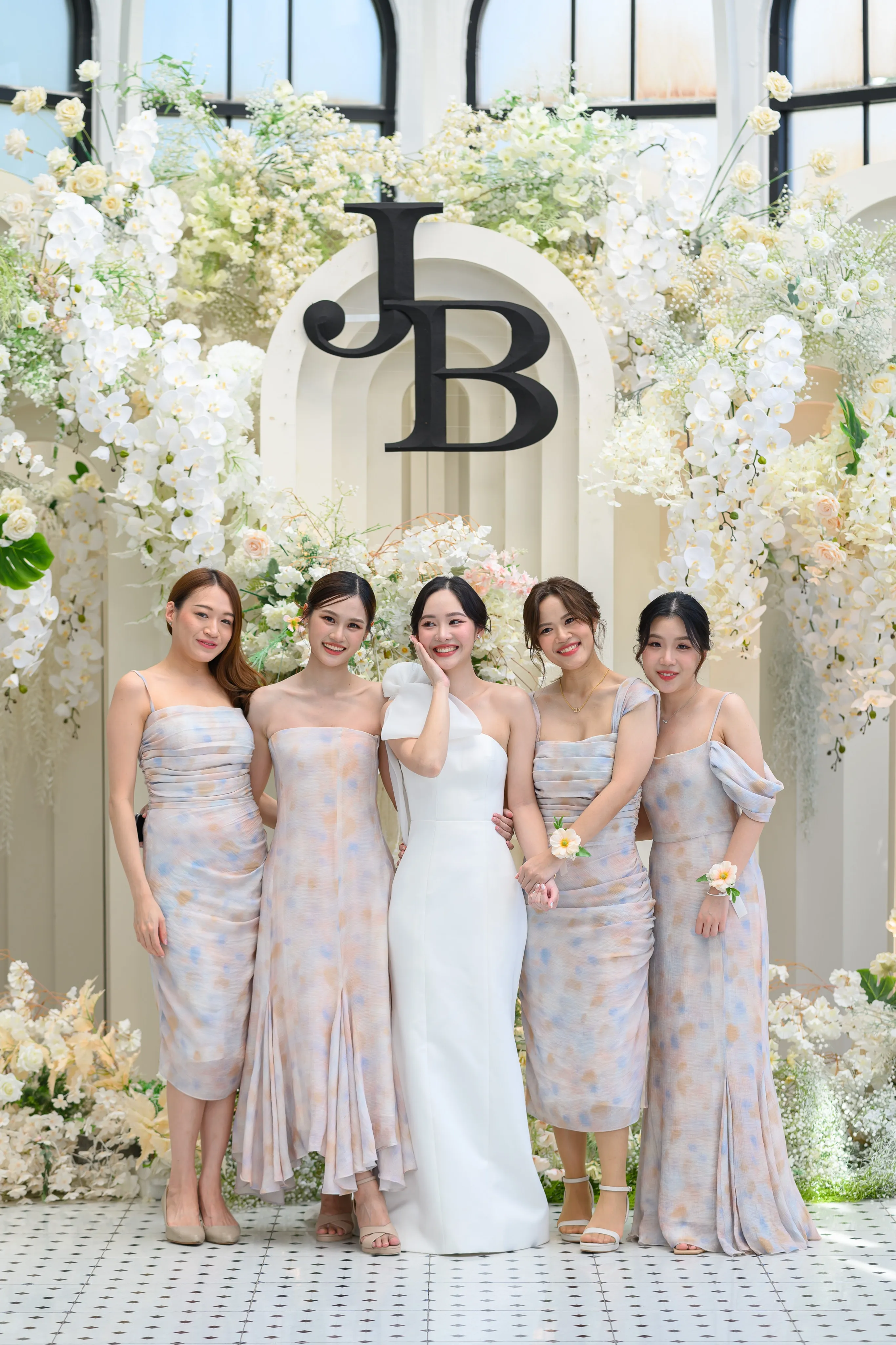 Bridesmaids posing beneath a floral arch