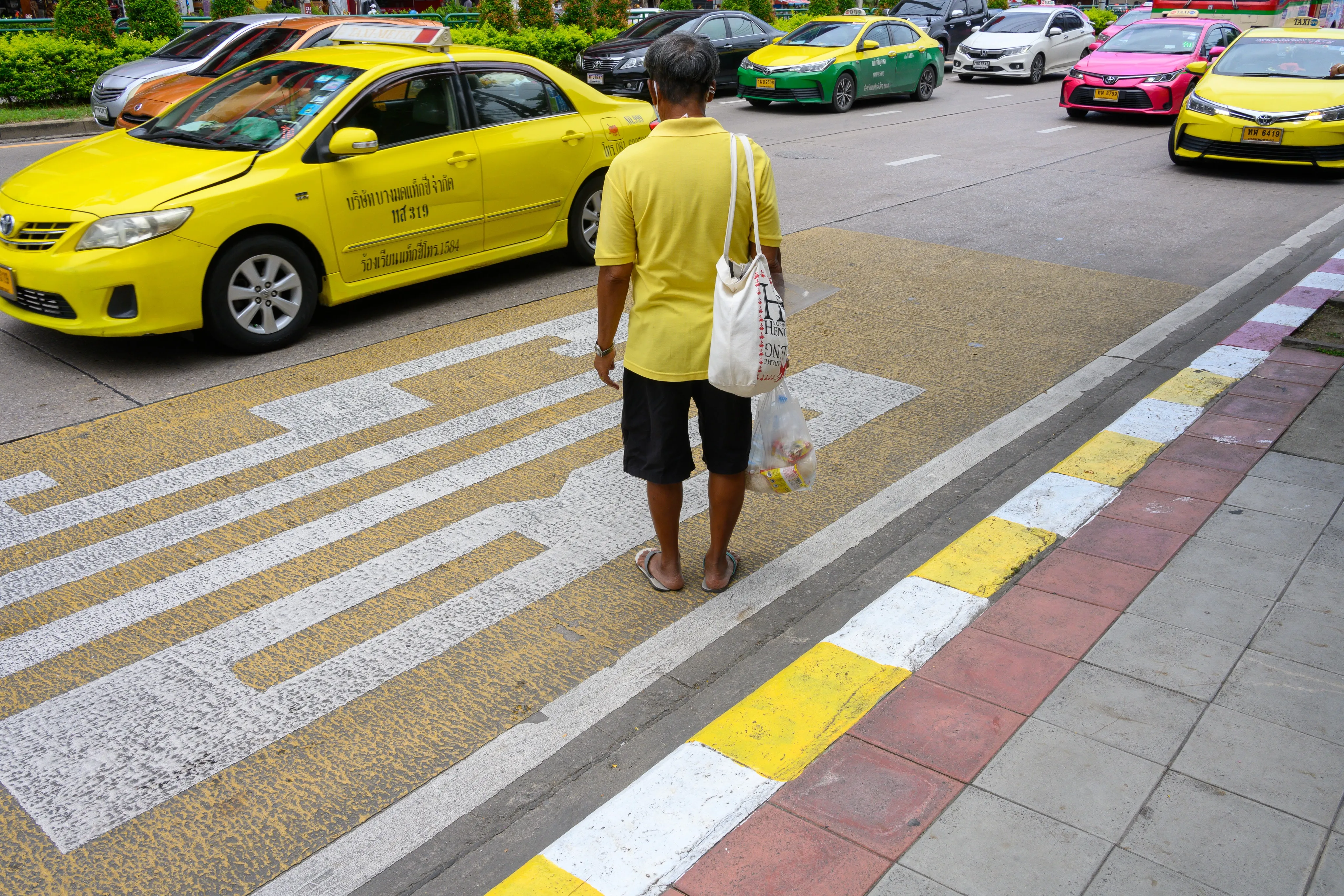 Traffic attendant signaling beside a line of brightly colored taxis