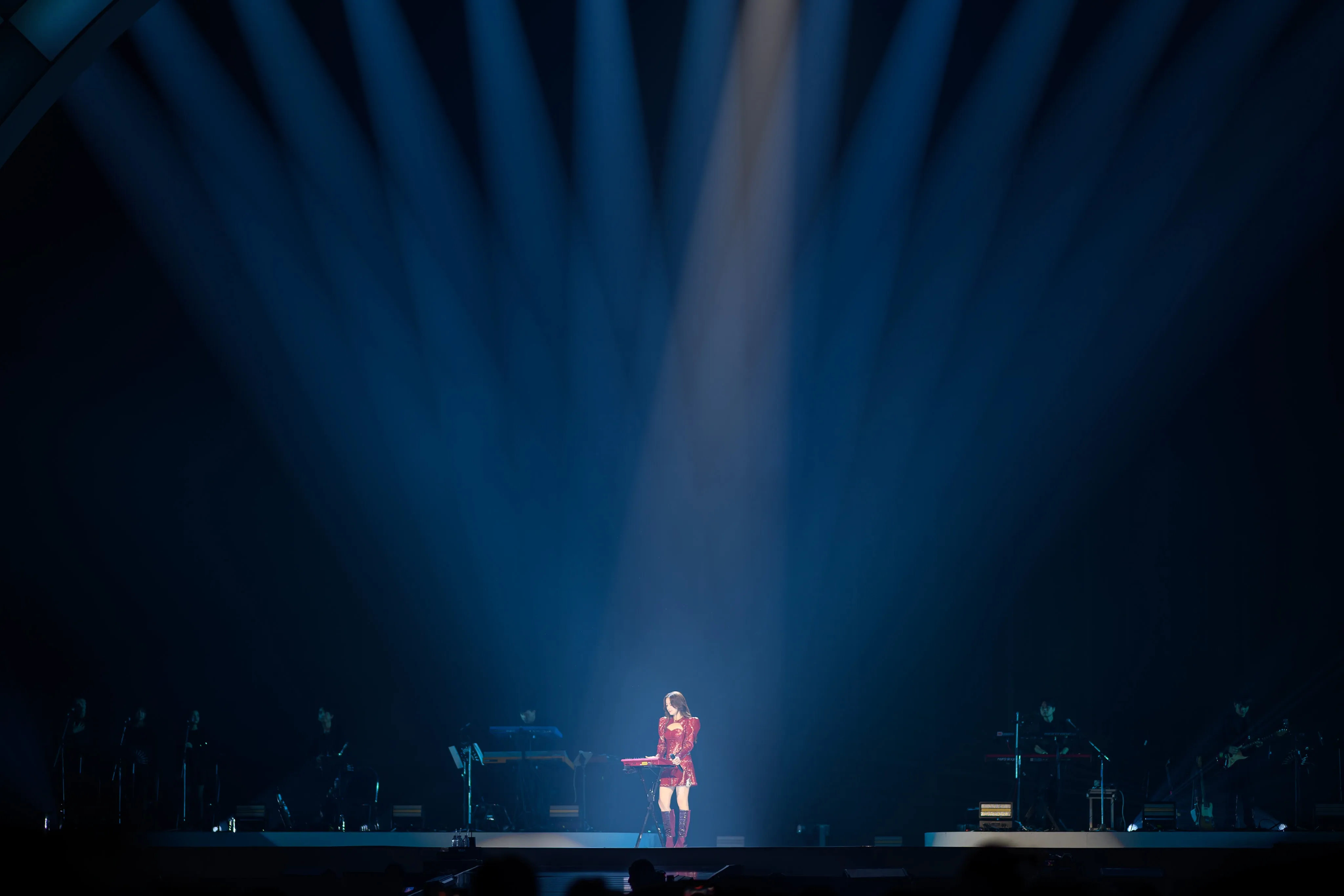 A singer beneath a fan of blue stage lights