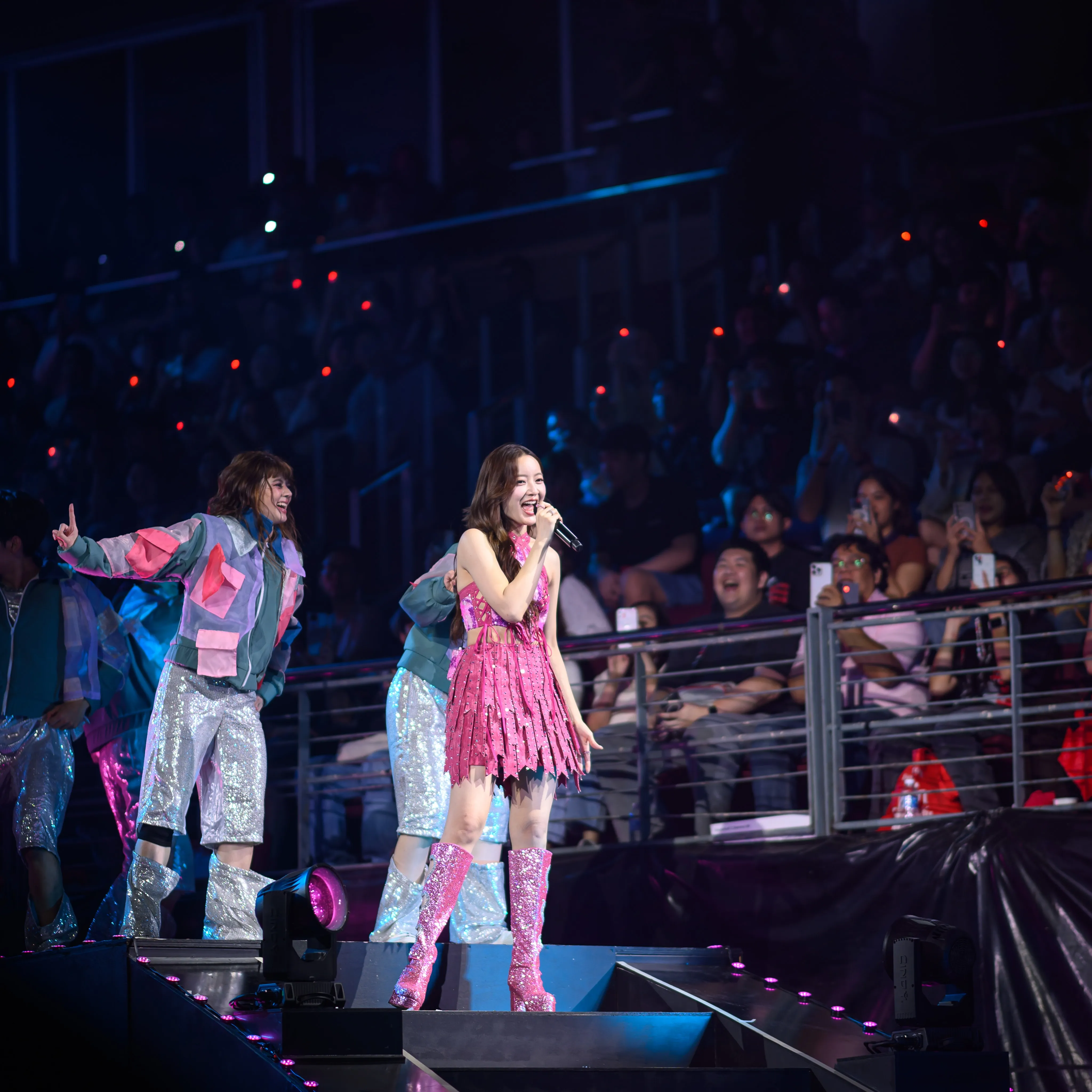 A singer in pink performing beside dancers