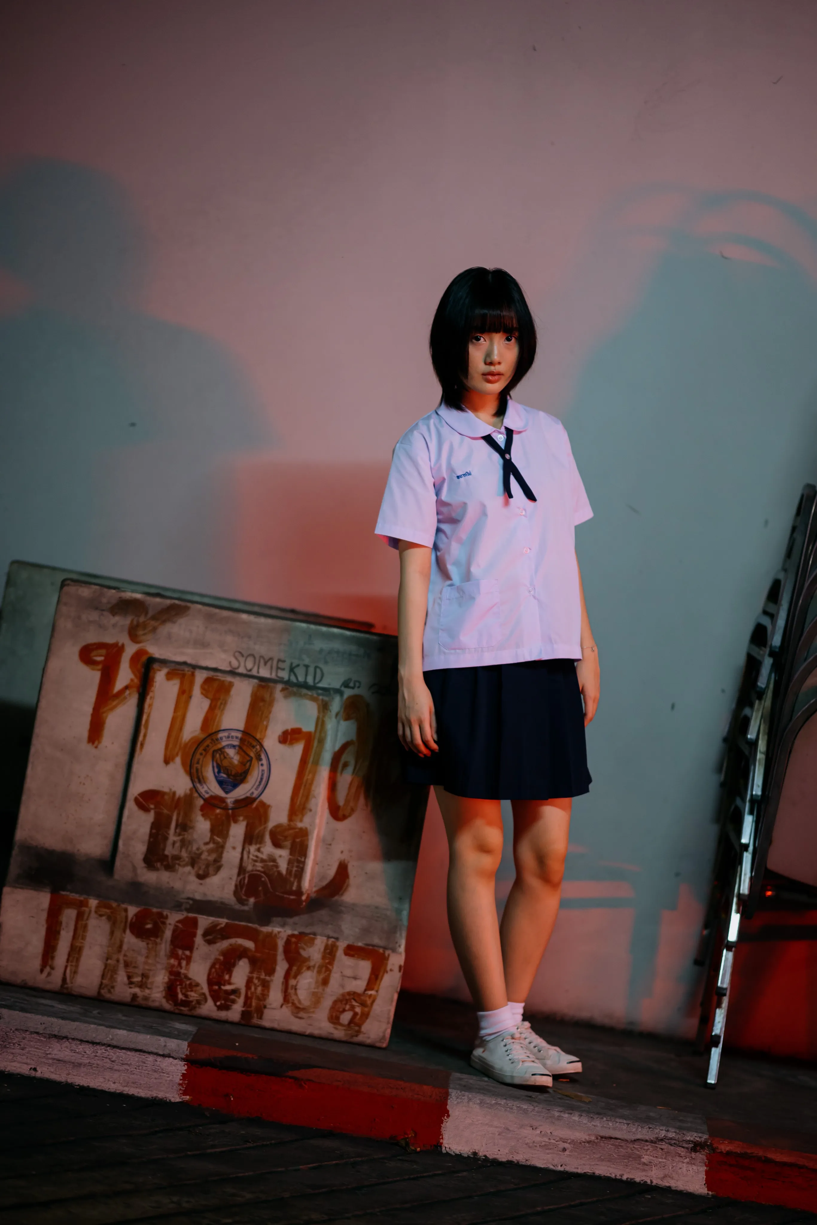 A young woman in a school uniform beside an illuminated red sign