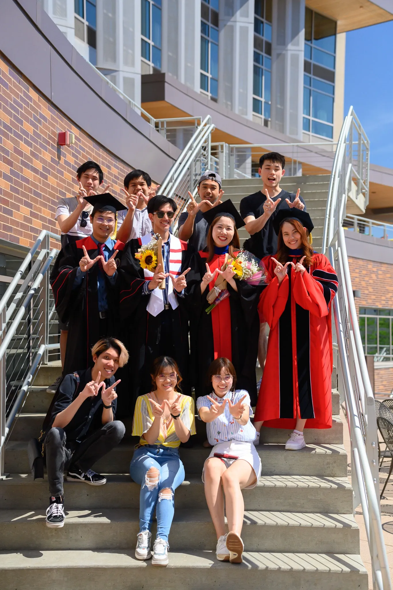 Group of graduates and friends posing on a campus staircase