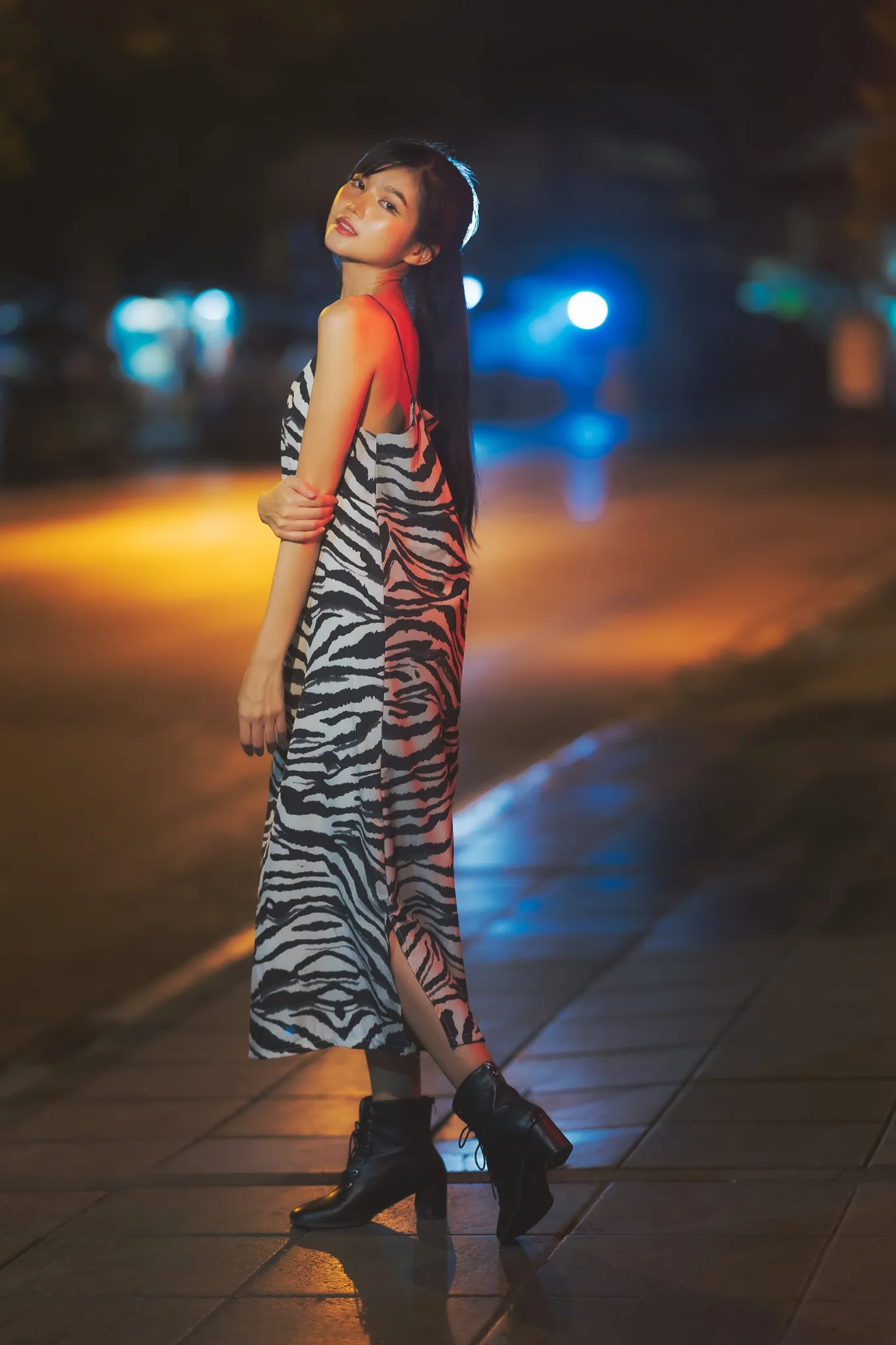 Woman in a striped dress posing at night amid colorful city lights
