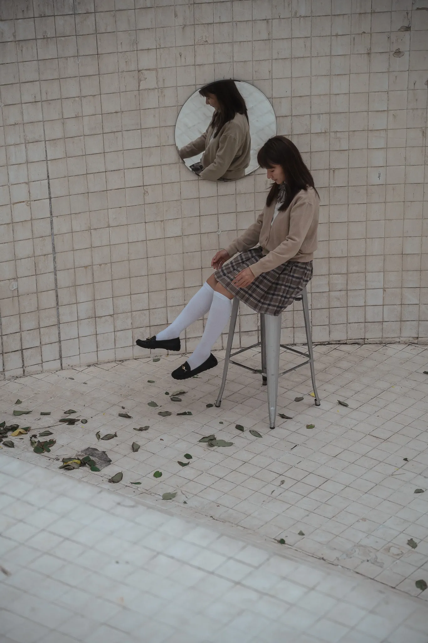 Woman seated on a chair in a tiled room with scattered petals