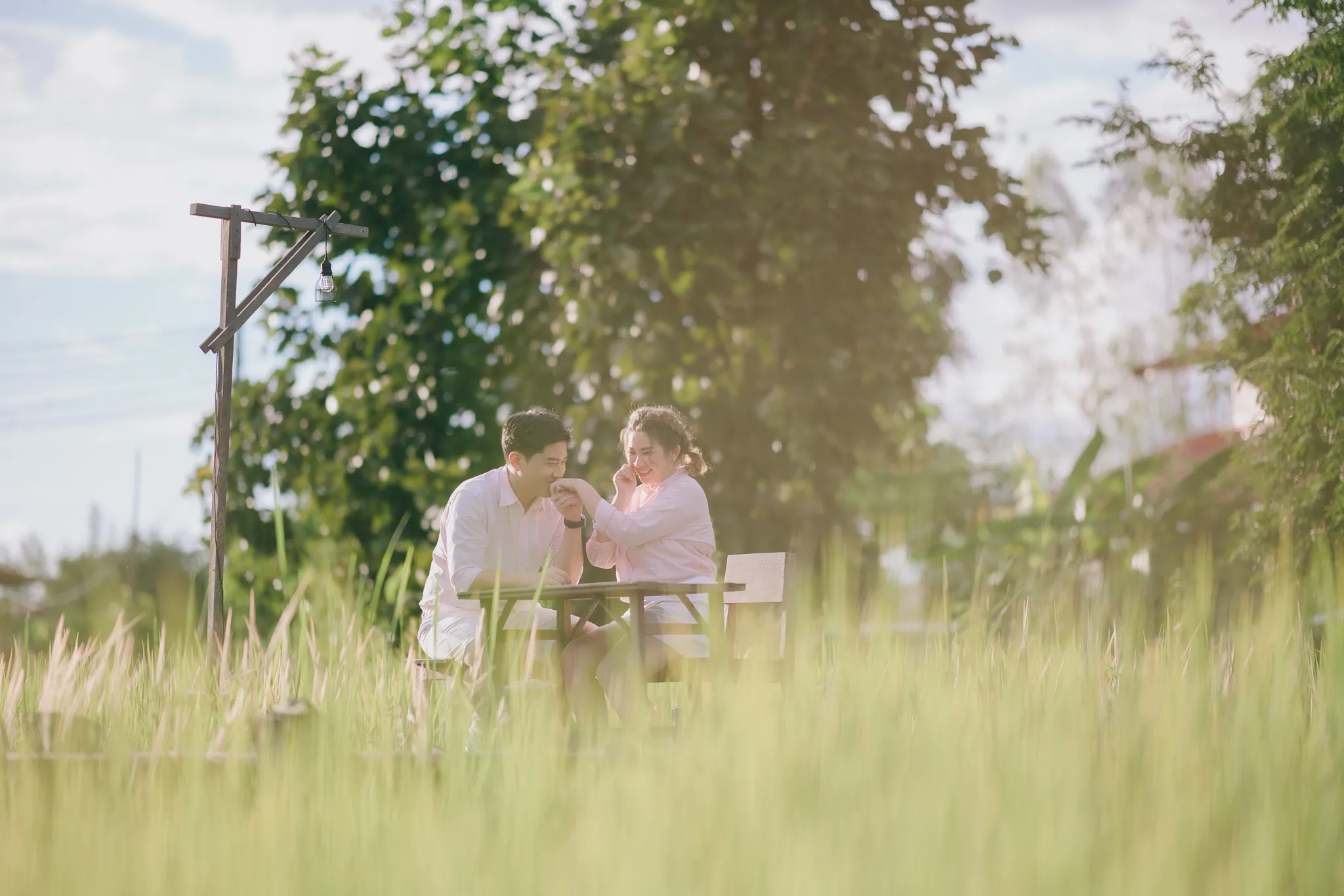 A couple in pink sitting at a table in a field of tall grass