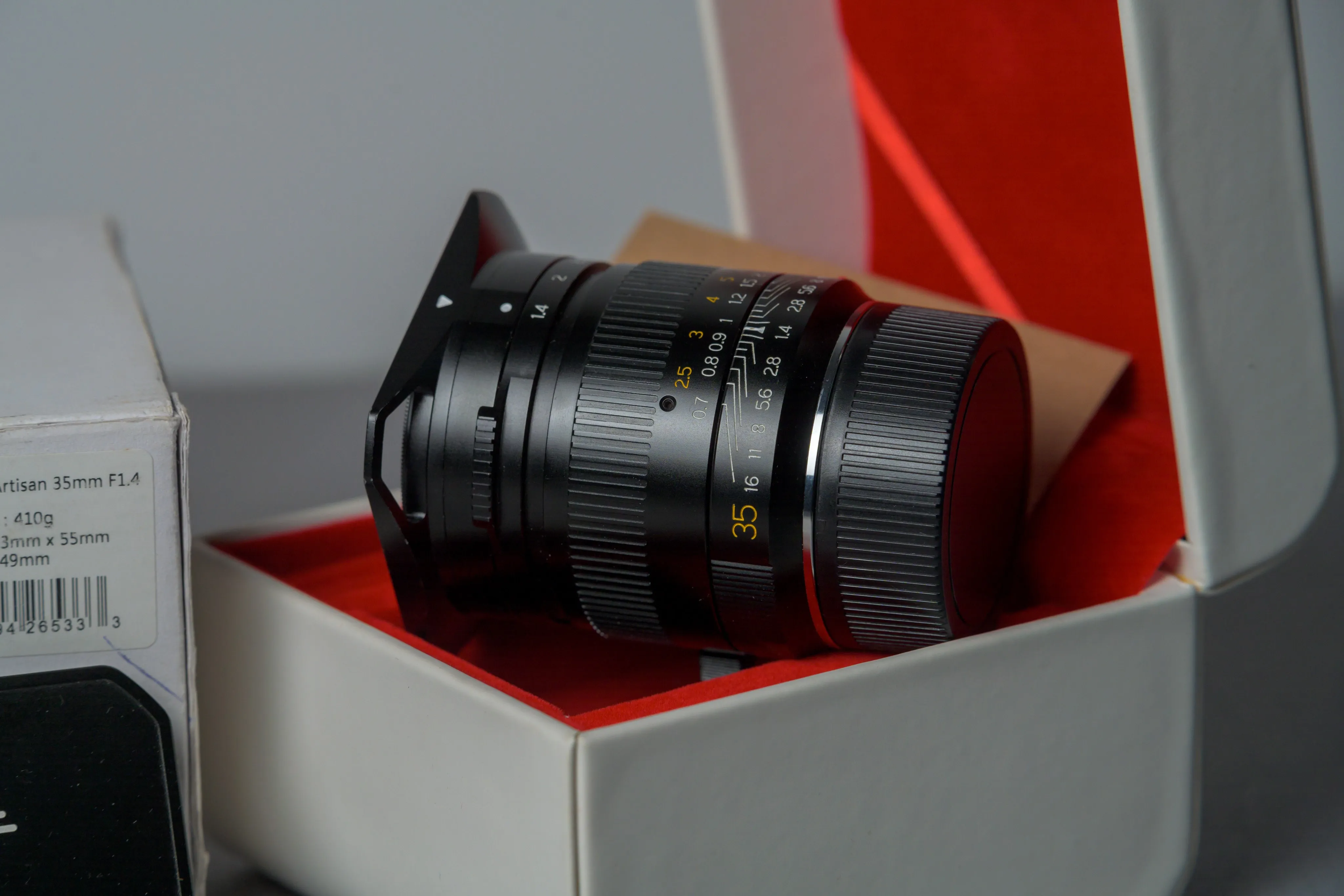 Camera lens displayed inside an open box with red interior