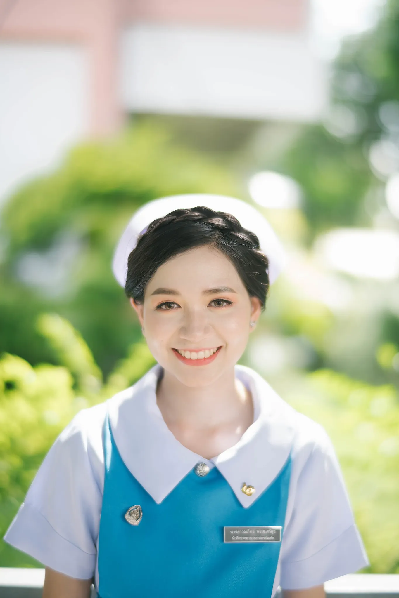 A graduate smiling in a blue-and-white uniform outdoors