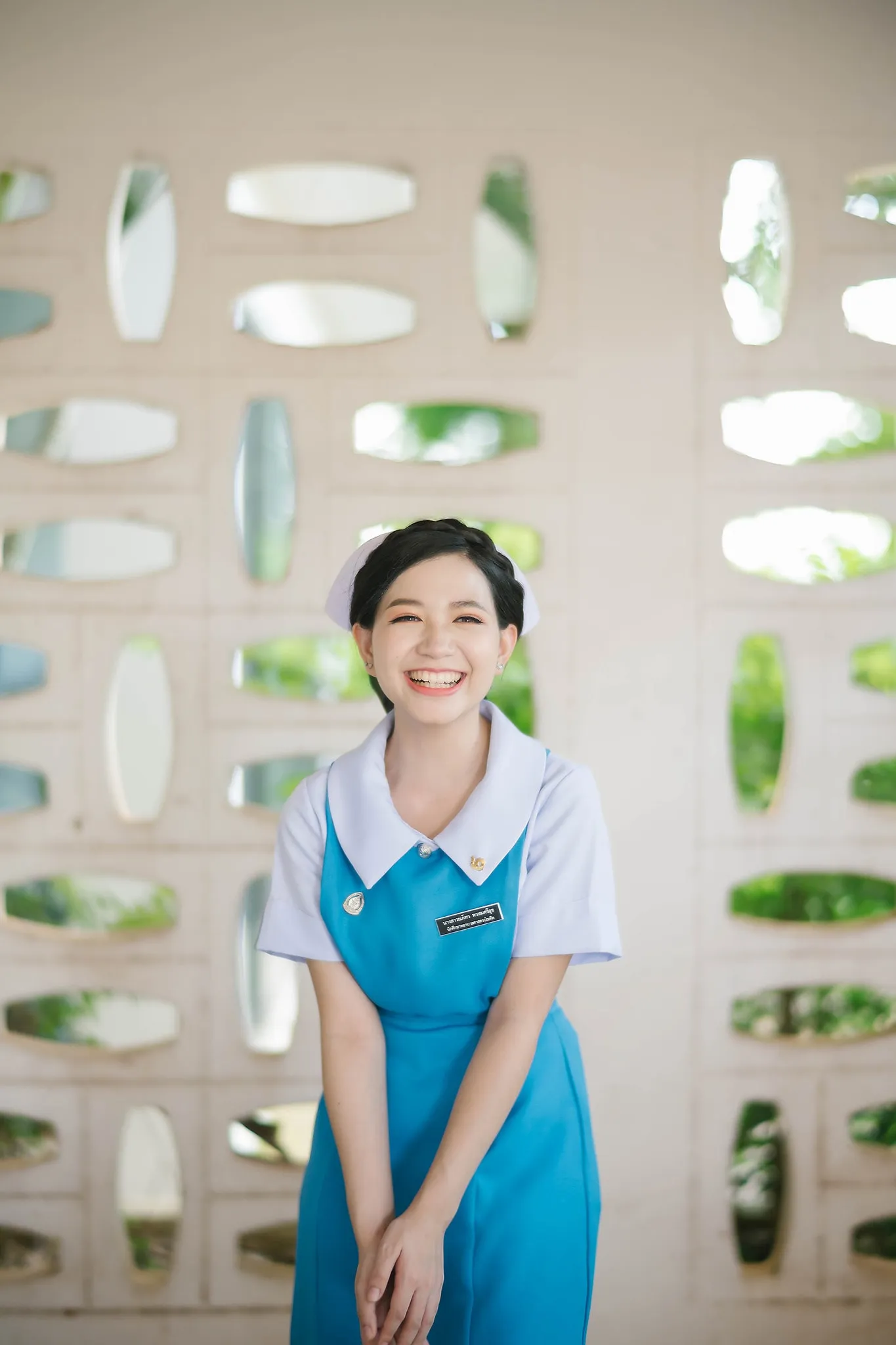 A graduate seated beside a patterned concrete wall