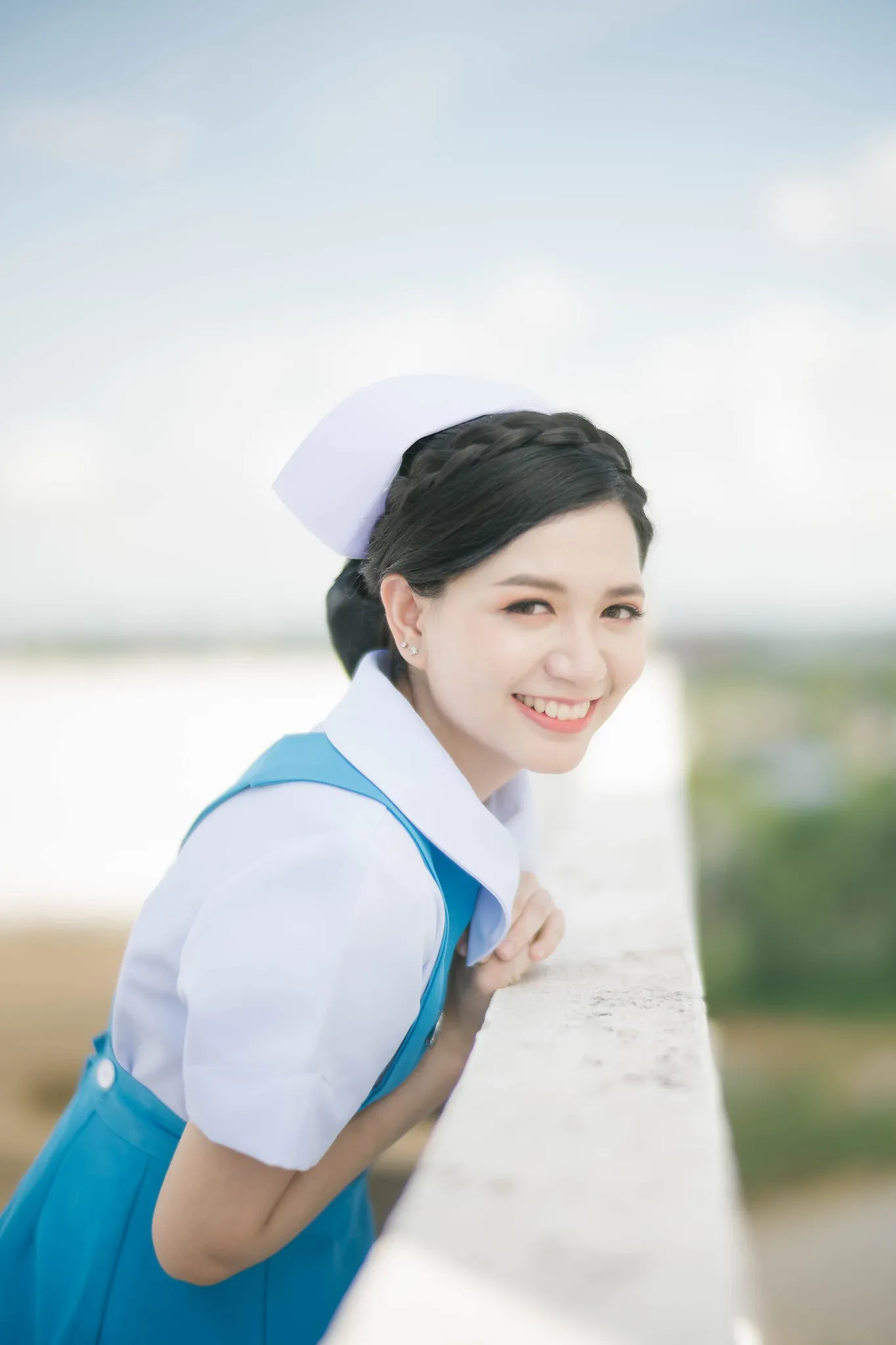 A graduate leaning playfully over a sunlit balcony