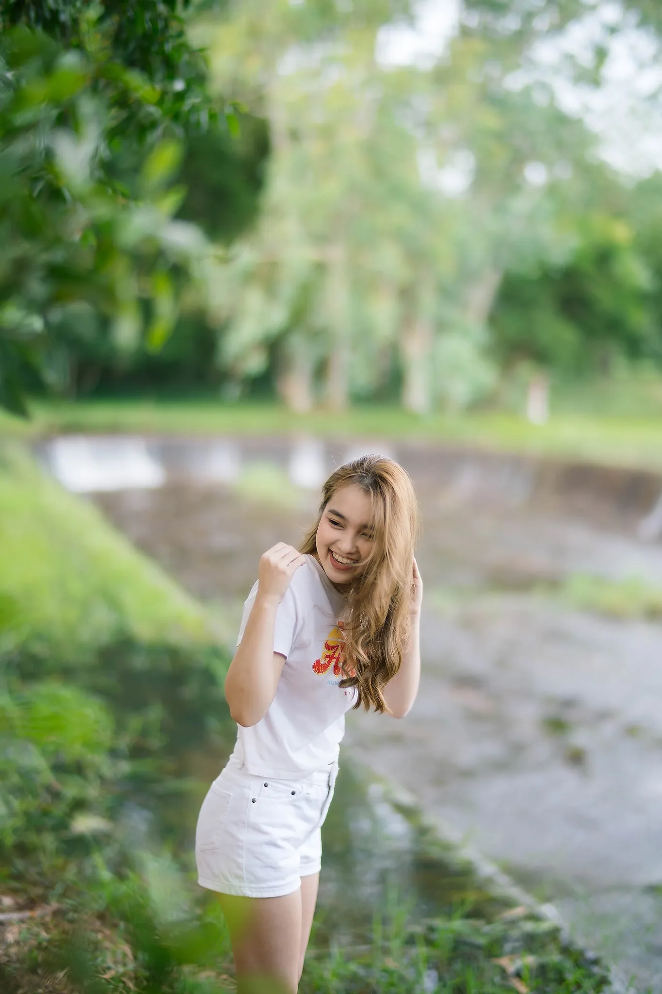 A woman in white posing beside a garden pond