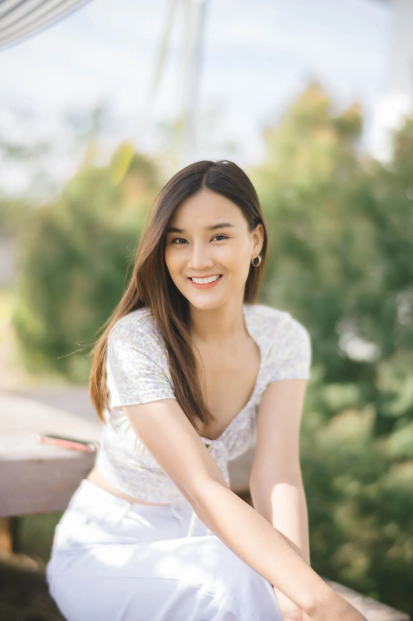 A woman in a white dress seated outdoors in soft light