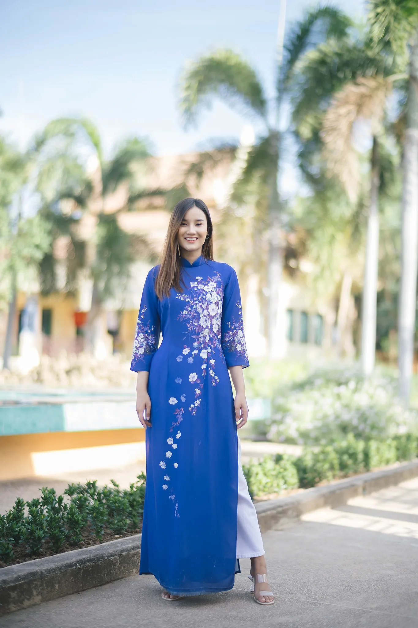 A woman wearing a blue floral ao dai in a courtyard