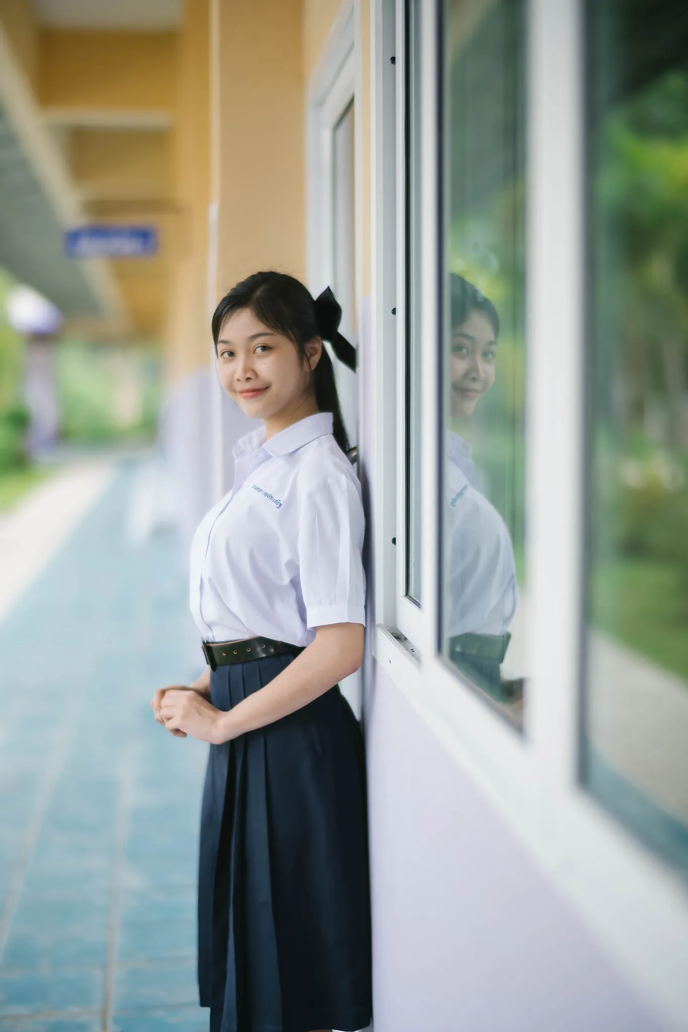 A student in a white blouse standing beside classroom windows