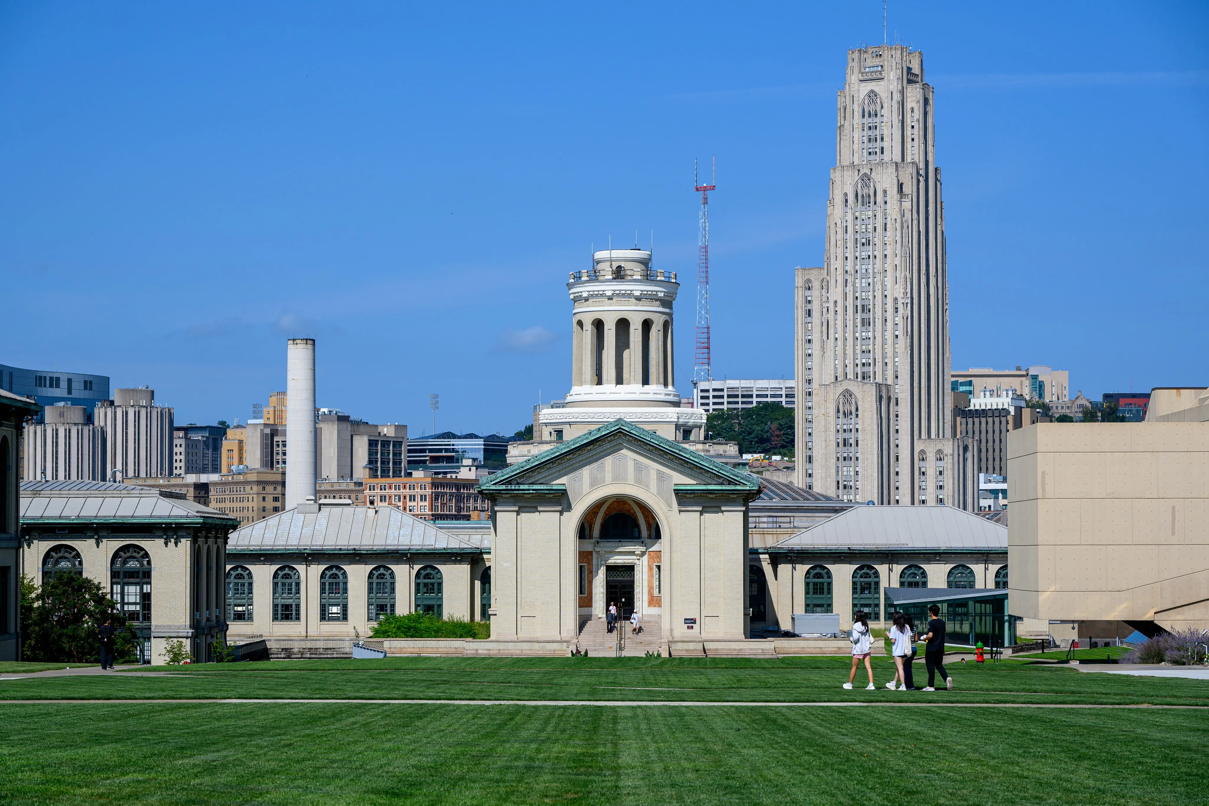 Campus lawn and academic building with the Cathedral of Learning rising behind it.