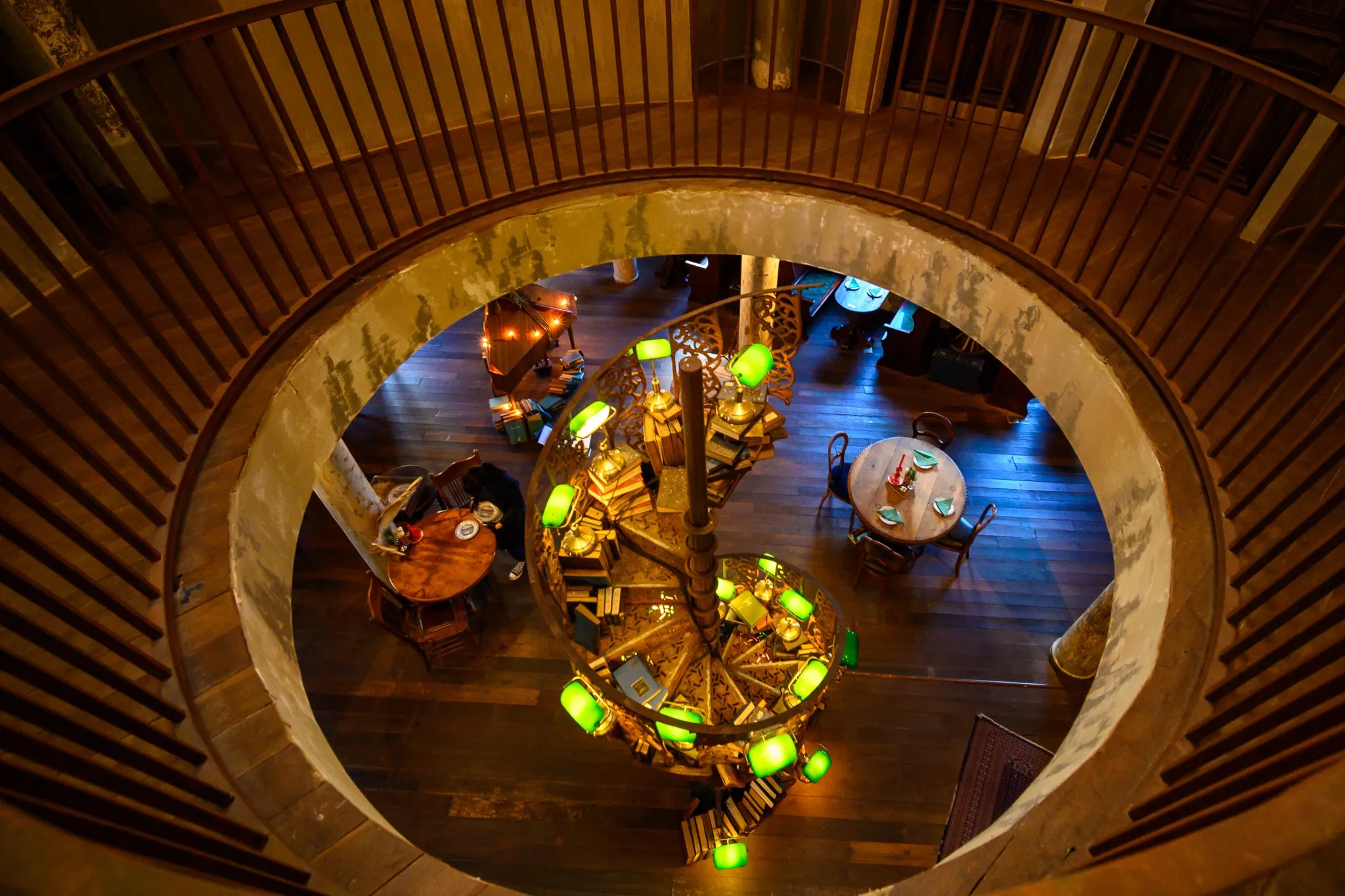 Looking down through a round atrium onto a café lit by green lamps