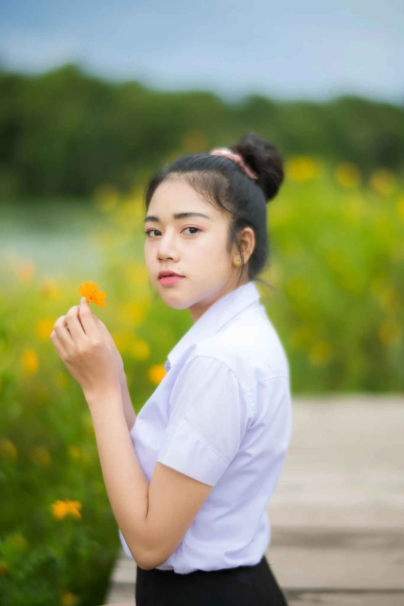 A student holding a yellow flower in a green field