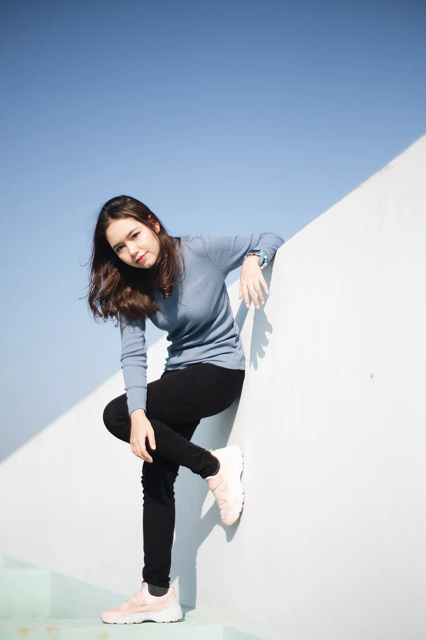A woman in athletic clothes posing against a geometric white wall