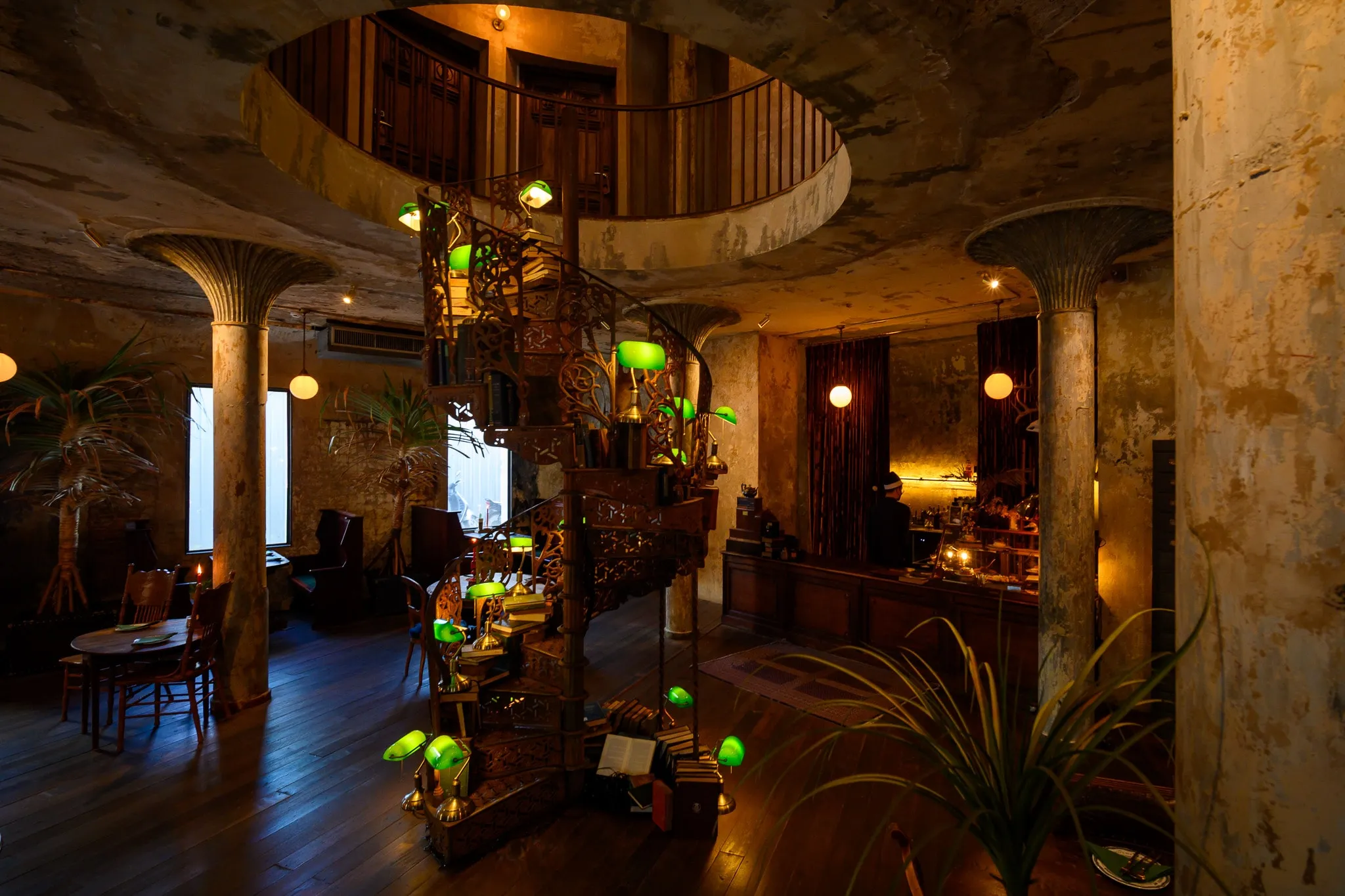 A café with mushroom-shaped columns around an atrium and green-shaded lamps