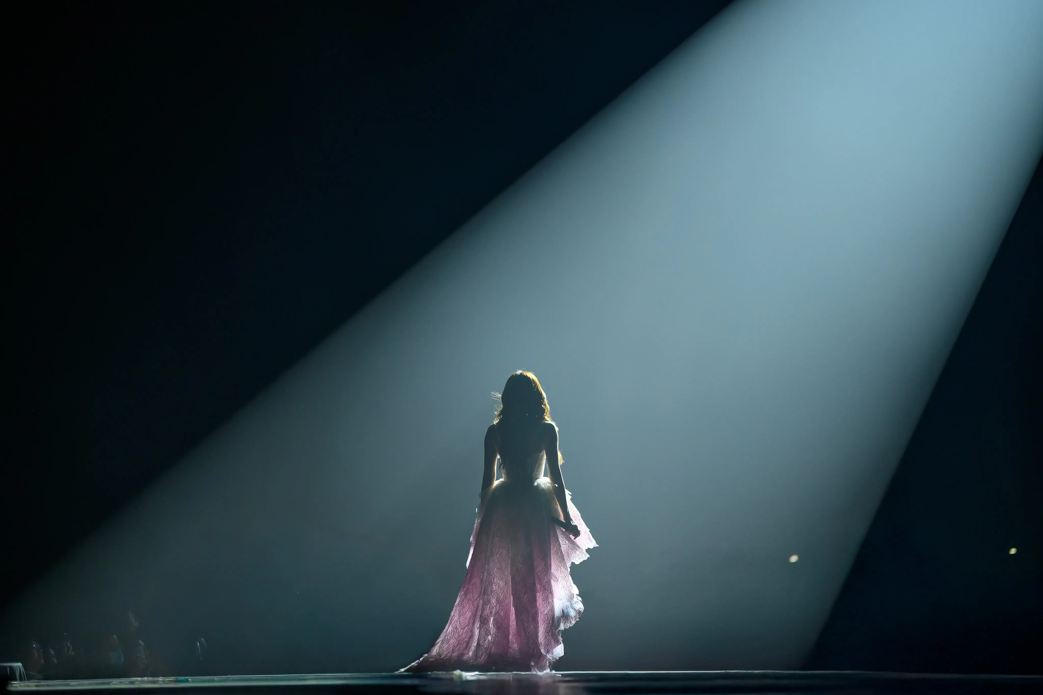 A performer in a flowing dress under a single spotlight
