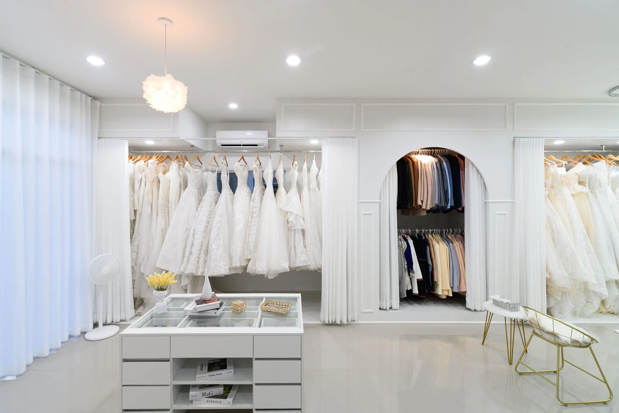 Racks of white gowns and an arched suit closet in a bright bridal studio